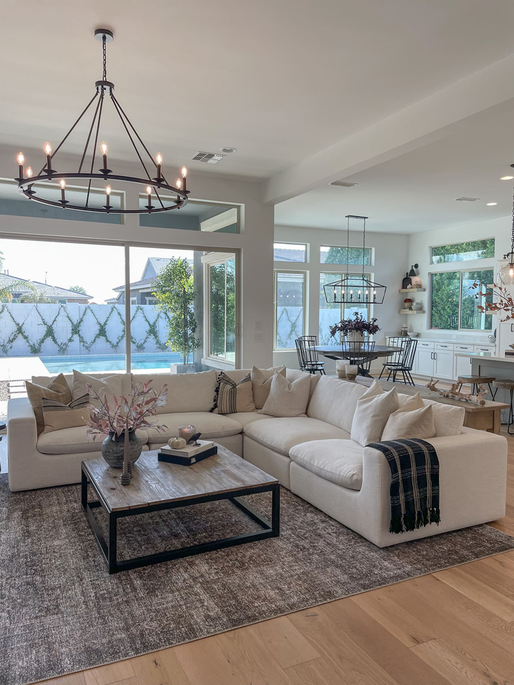 a L-shaped sofa on a rug in the middle of the room with a chandelier above it and many mid-century modern furniture