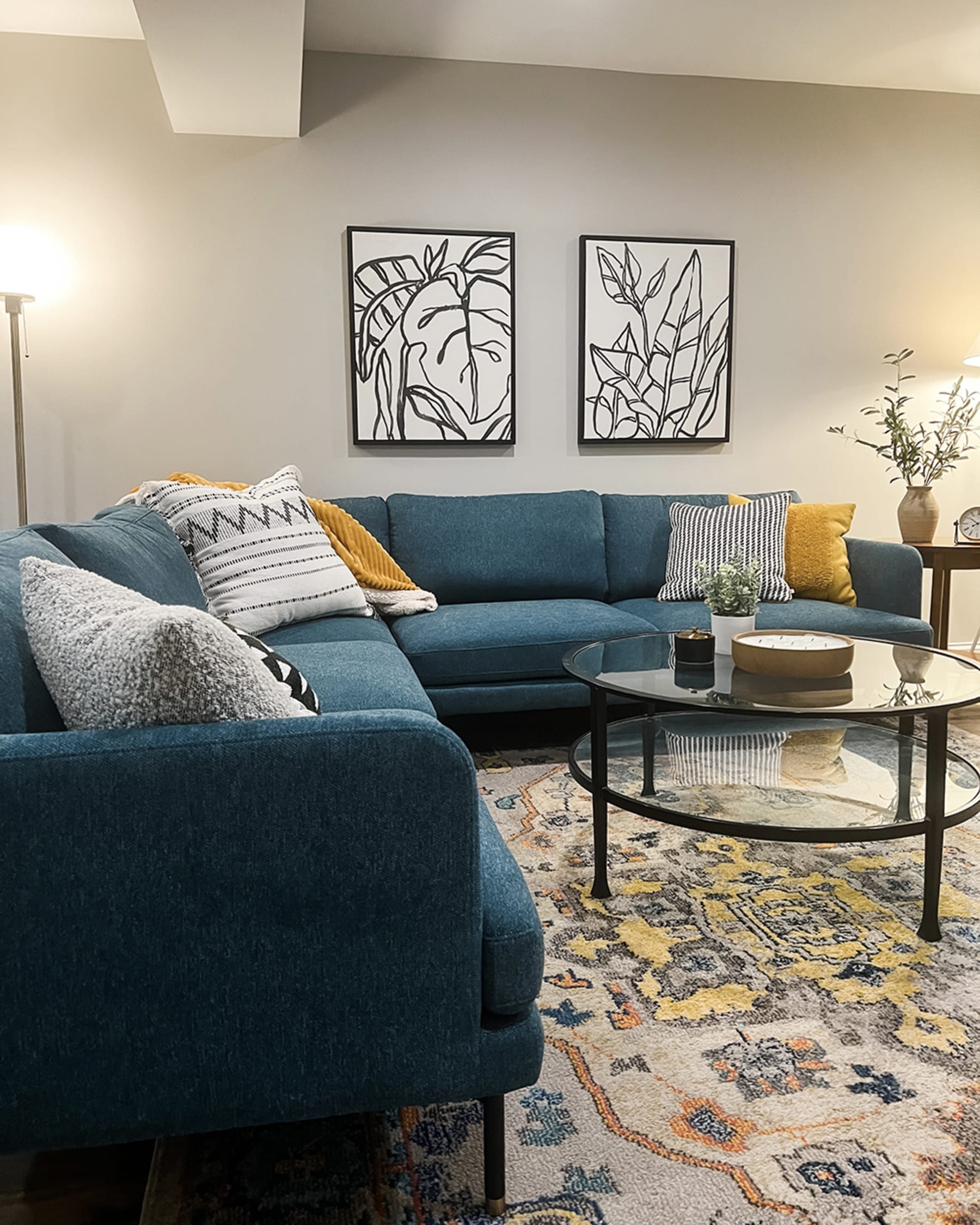 a bright blue L-shaped sofa on a rug paired with yellow and white cushions in a mid-century modern living room