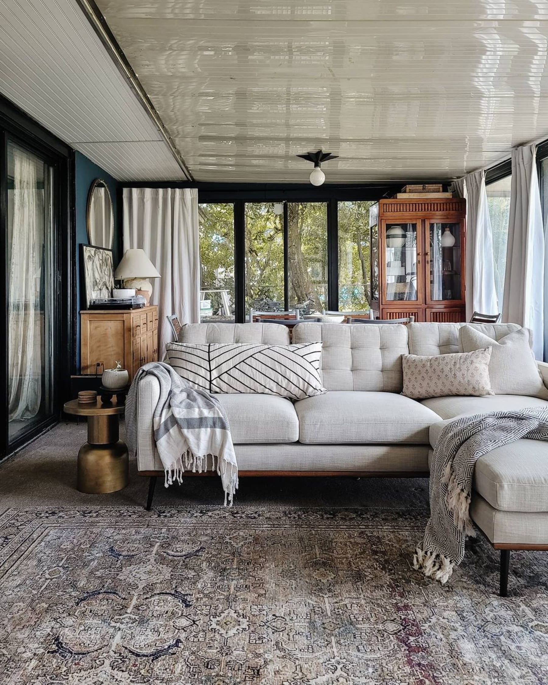 A gray reversible sectional chaise sofa decorated with accent pillows and throws, and complemented with a rug.