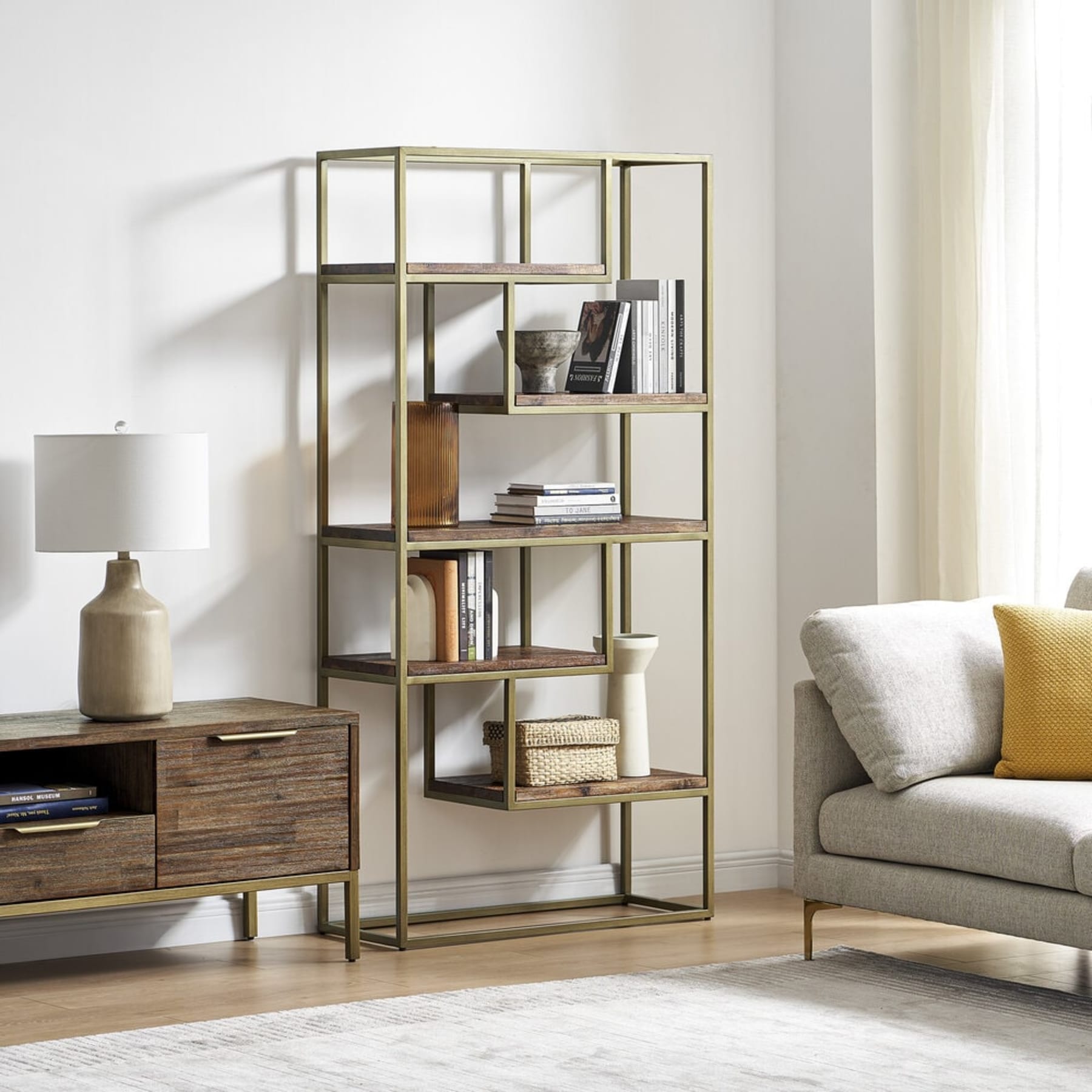 A wood and brass shelf rests against the wall, adjacent to a fabric armchair.