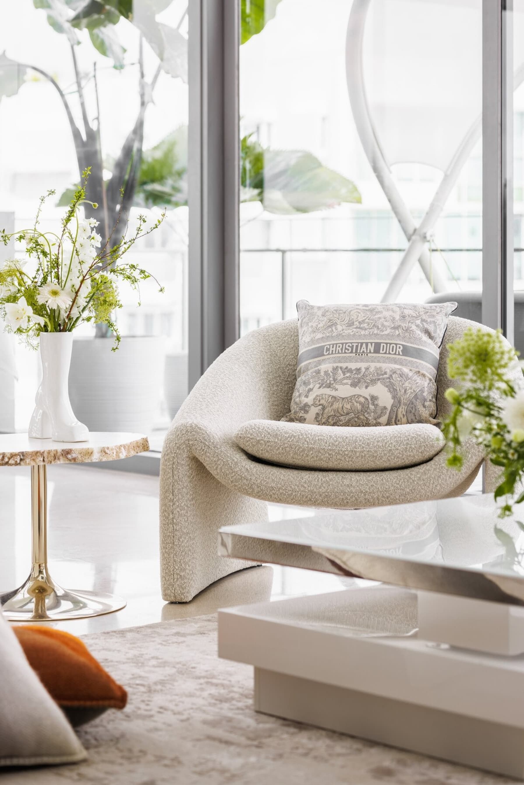 A bouclé armchair complements the white furnishings of the space.