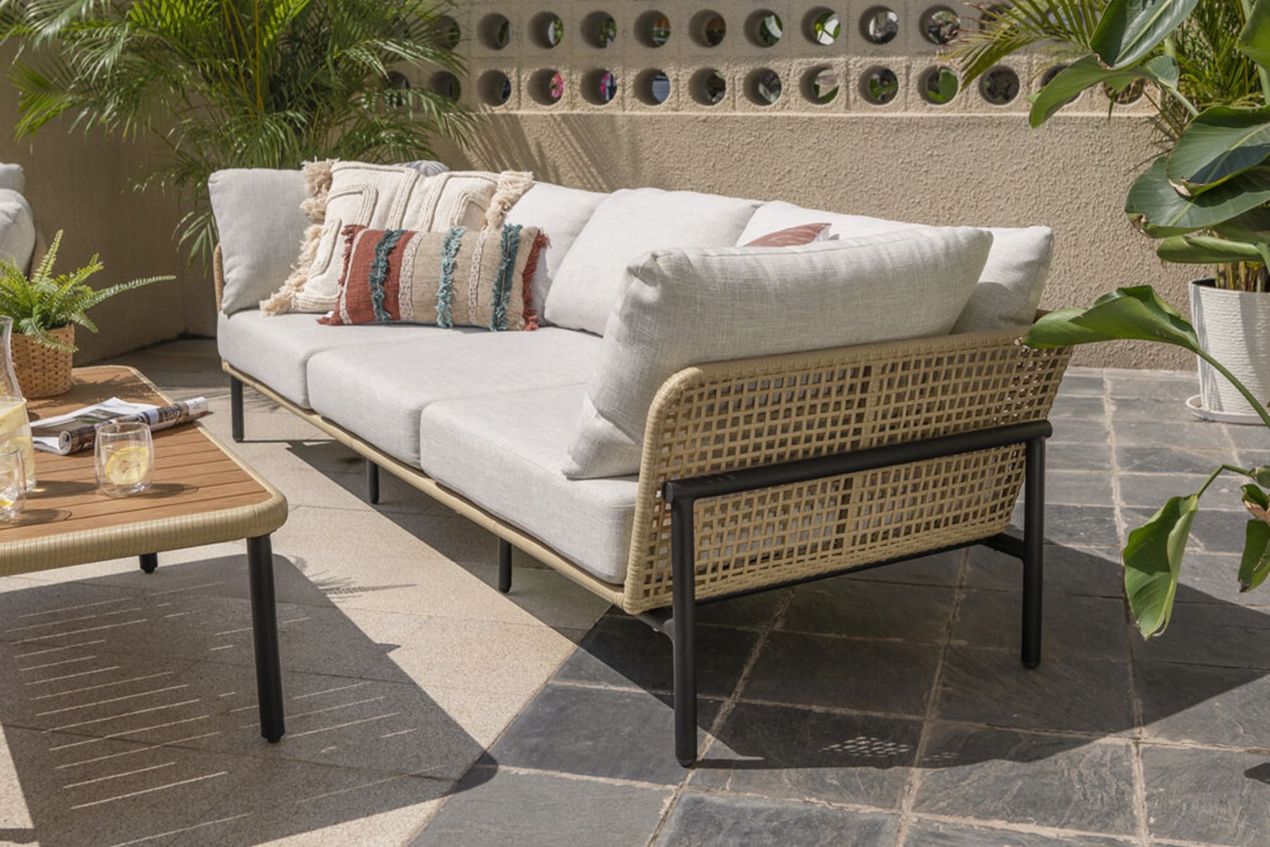 An outdoor sofa with a rattan sofa suspension and a black metal frame.