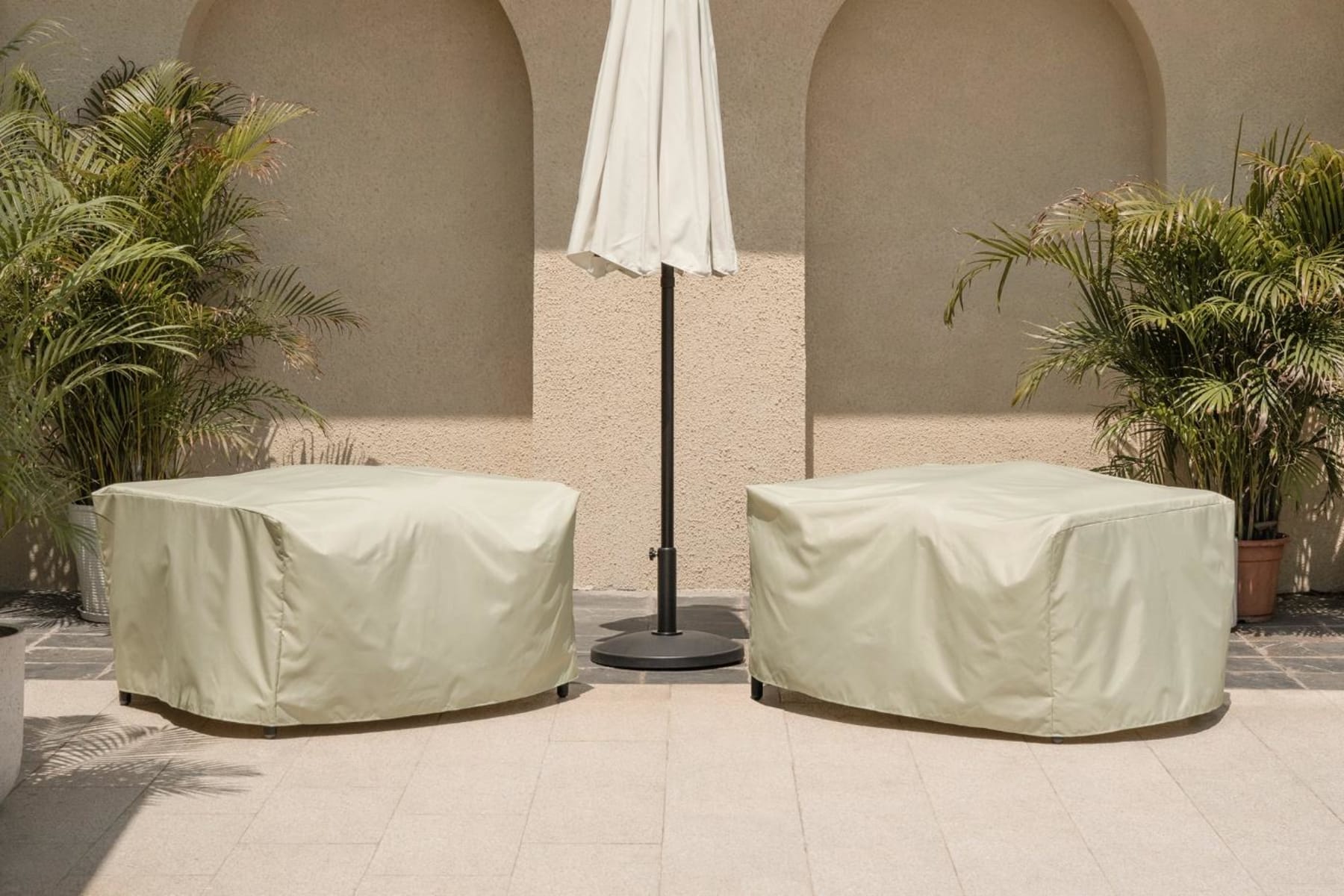 Two outdoor lounge chairs covered with protective furniture covers.