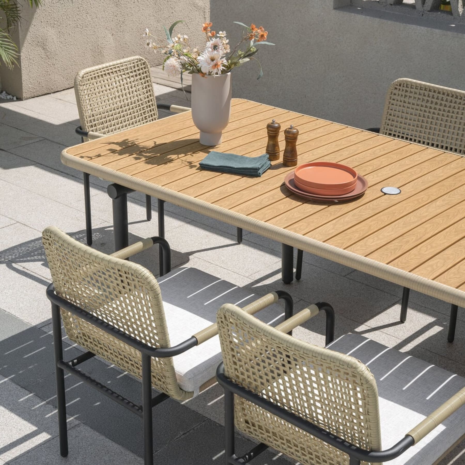 A resin wood dining table and rattan dining chairs.