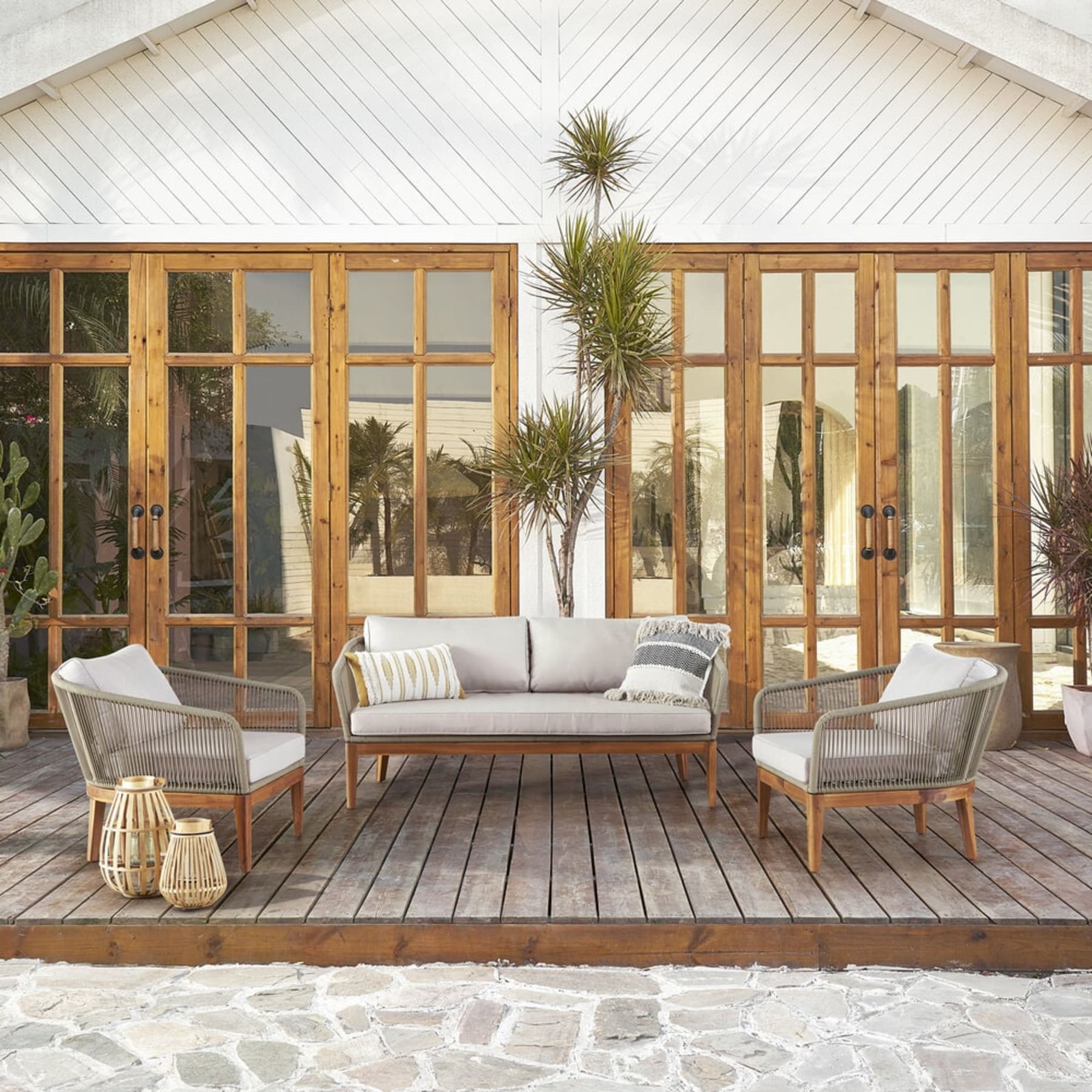 A loveseat and 2 lounge chairs sit on a wooden deck outdoors.