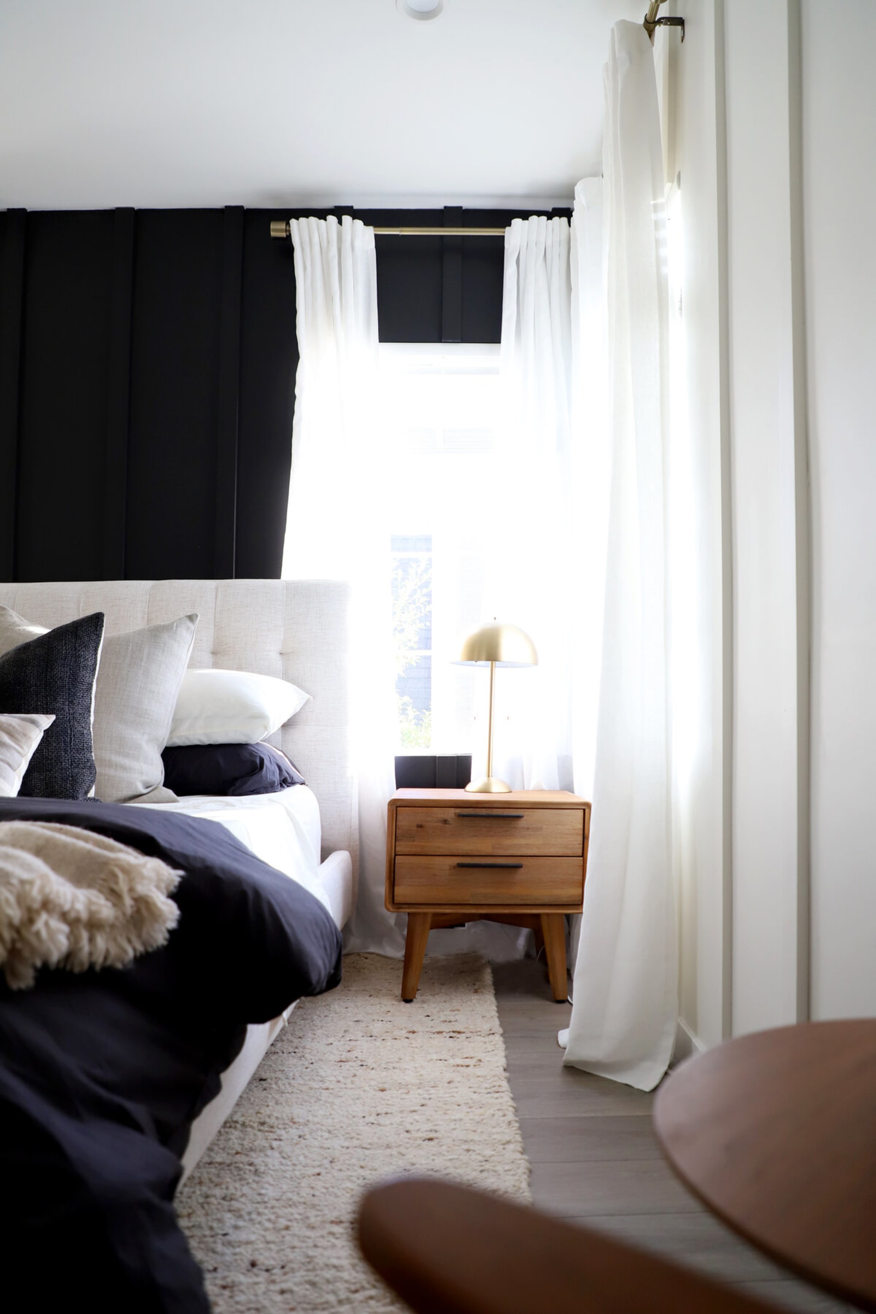 A wooden nightstand sits at the corner of a room beside the bed.