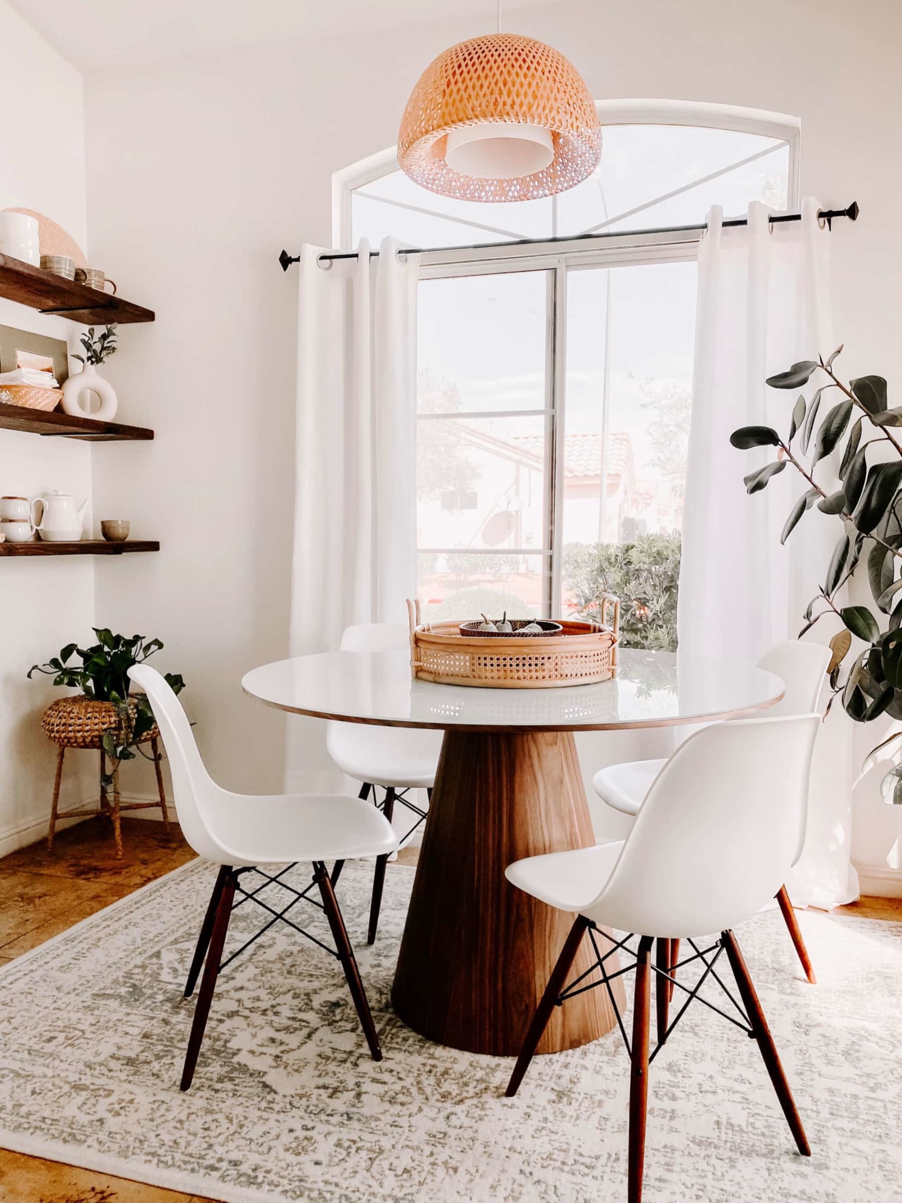 A round dining table with a glass table top and 4 white chairs.