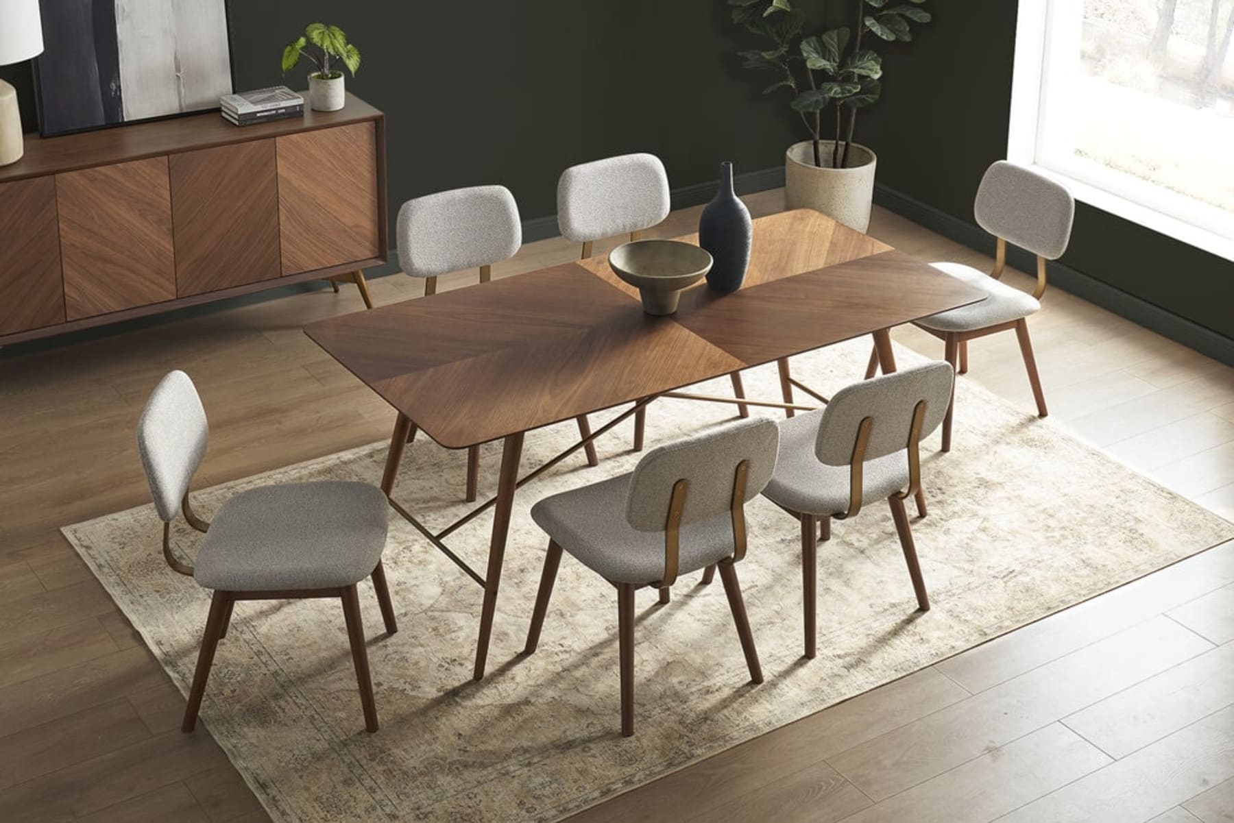 A marble dining table and cane chairs are centered on an oval jute rug.