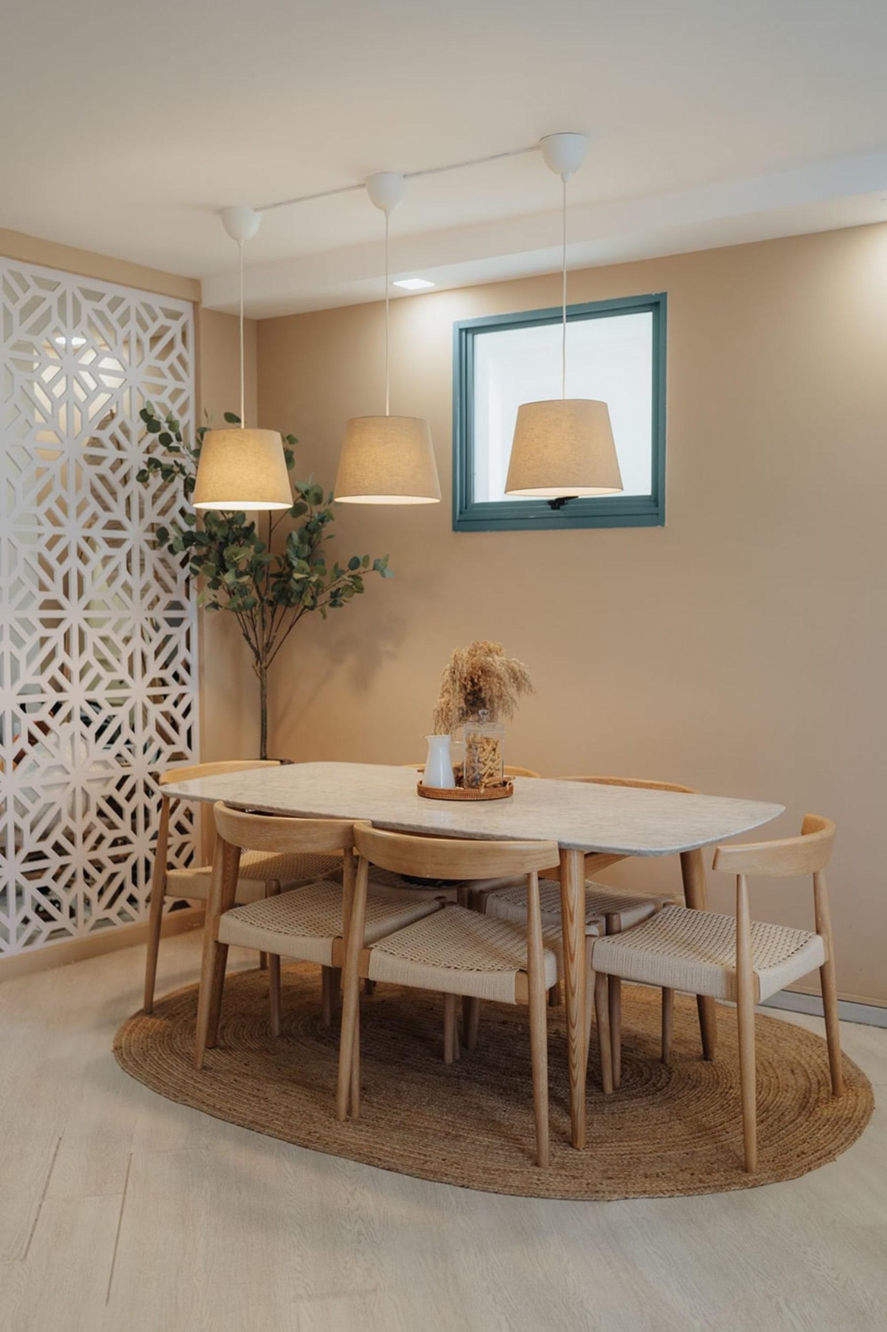 A marble dining table and cane chairs are centered on an oval jute rug.