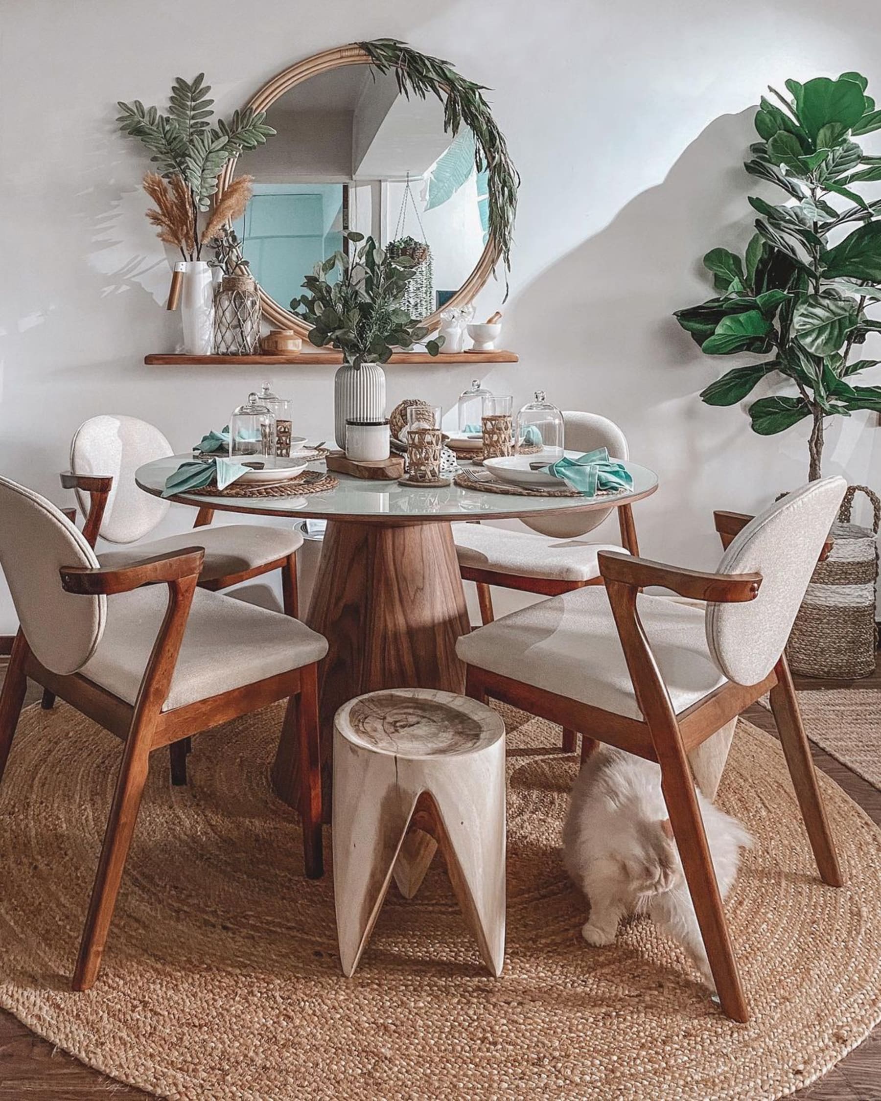 A white glass table top with a conical wooden base and fabric upholstered chairs.