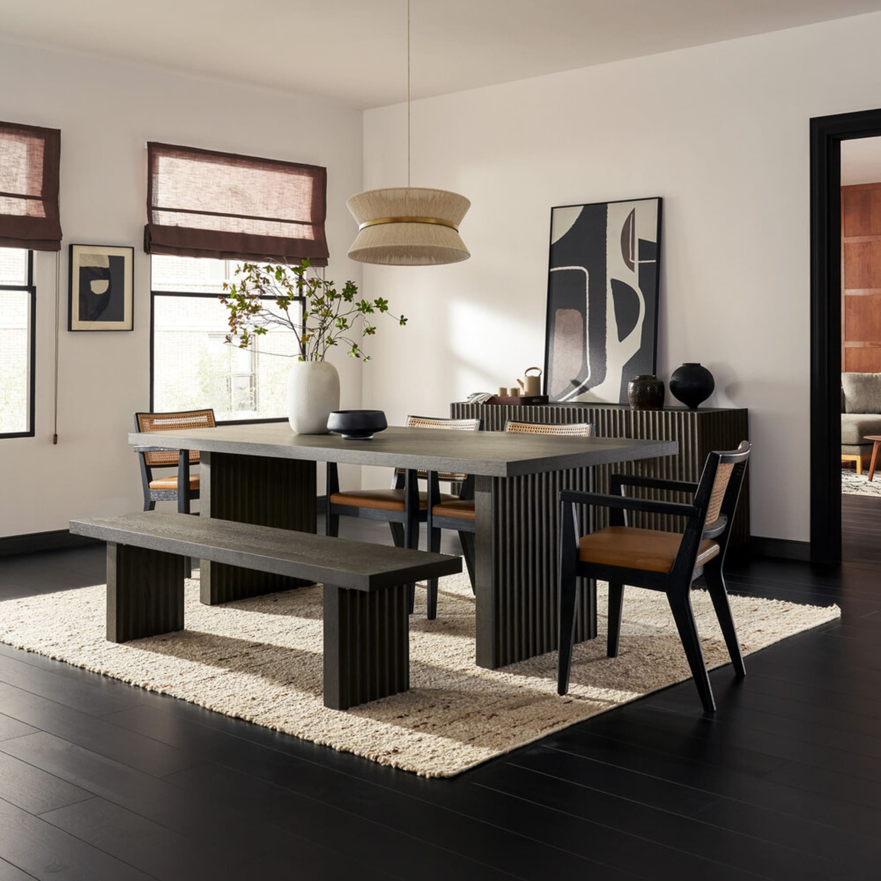 A black dining table with matching chairs and a bench.