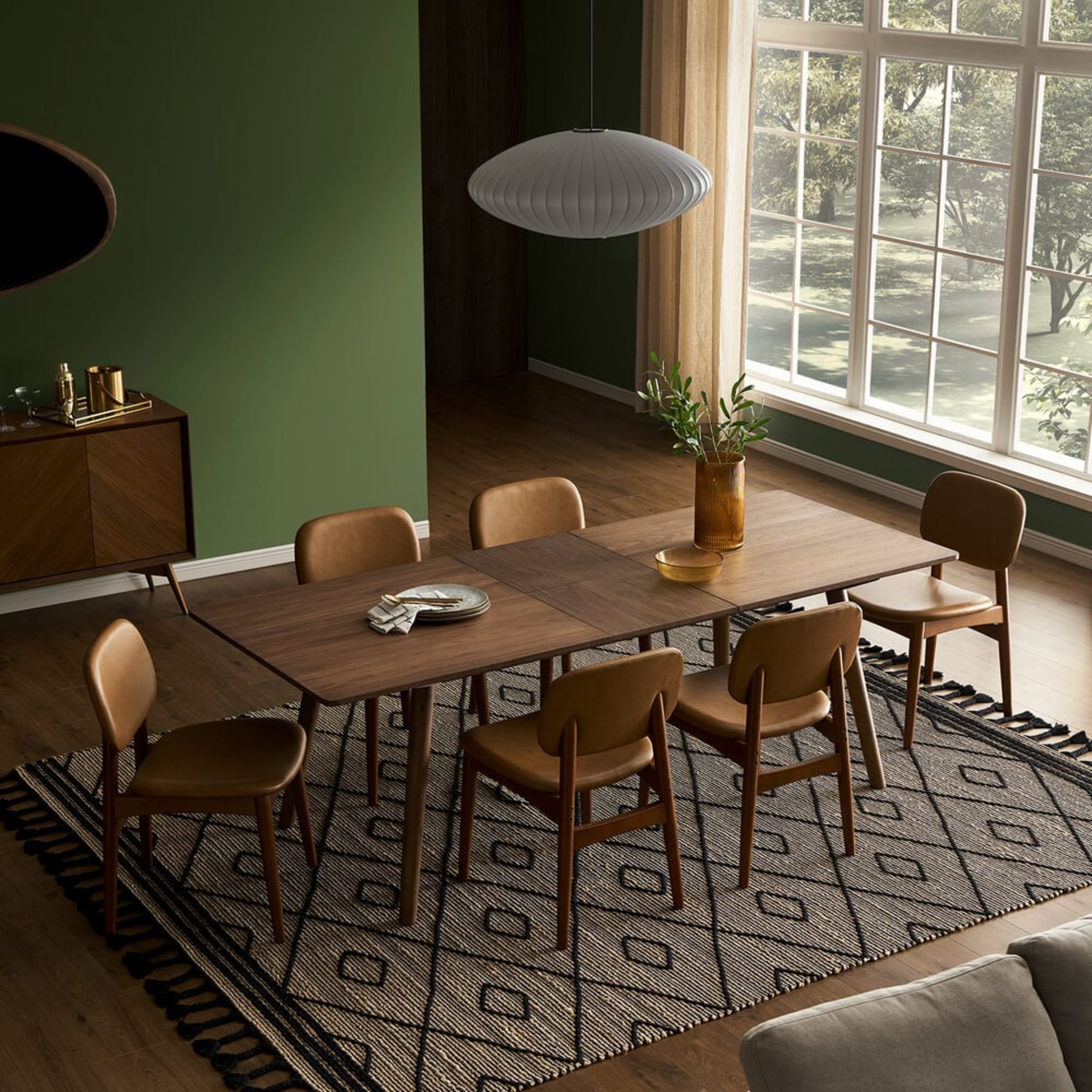 A wooden dining table sits atop a jute area rug.