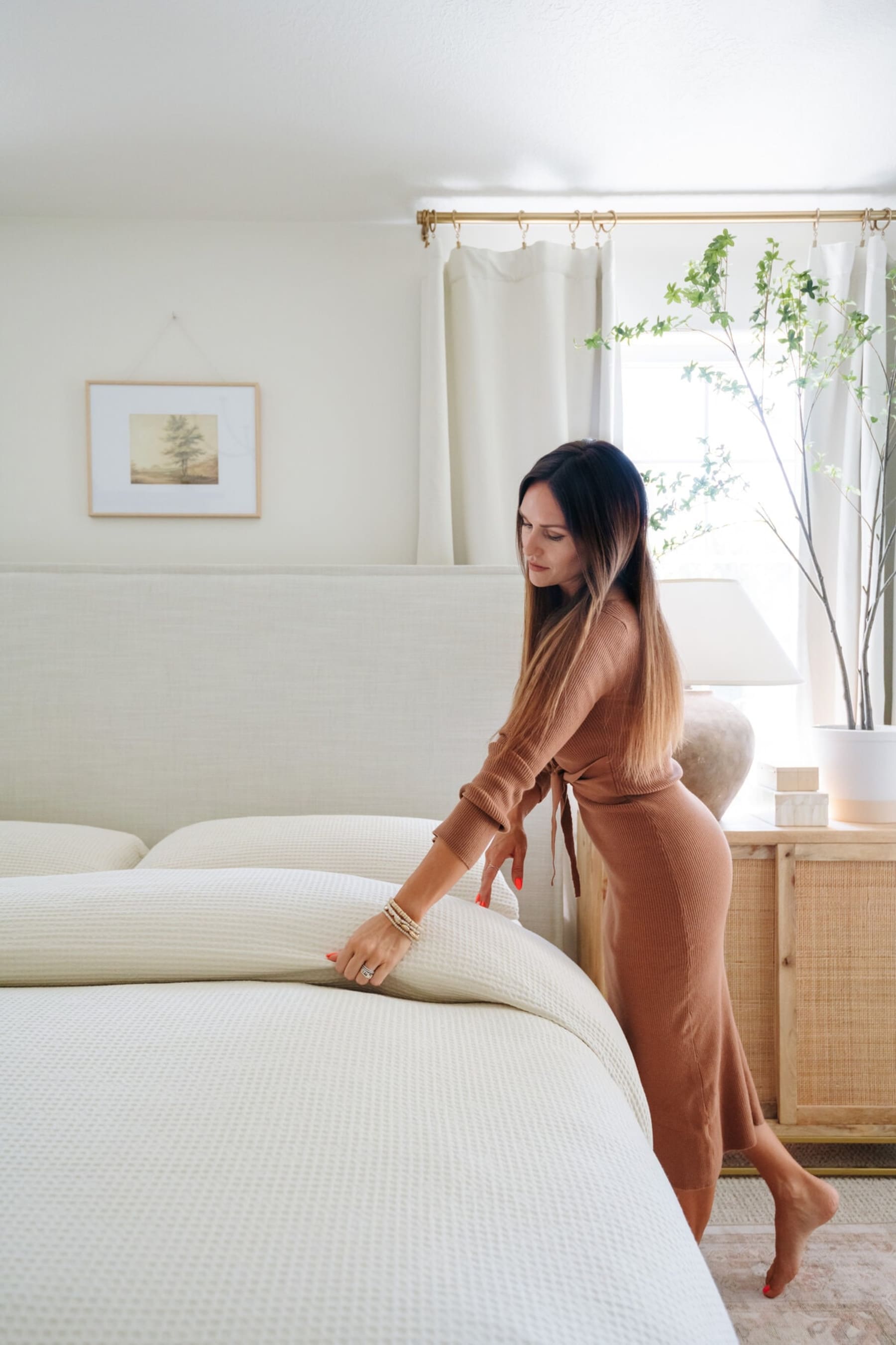 A person is straightening the duvet on the bed.