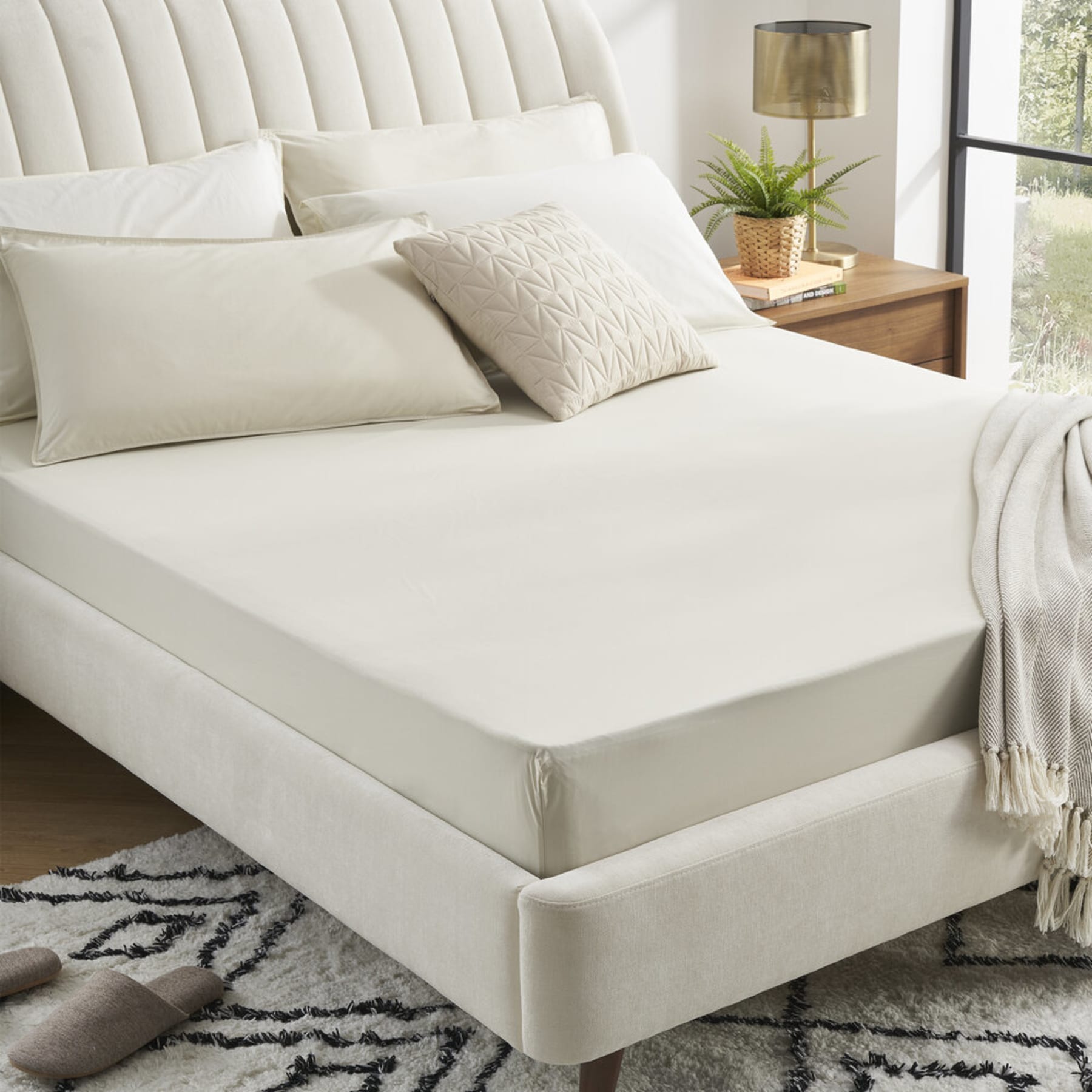 A percale bed sheet set shown on a tufted bed.