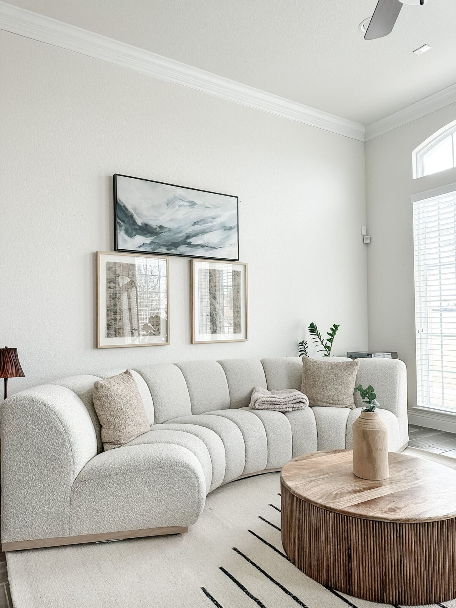 A performance fabric curved sofa with tufted seats sits atop a rug.