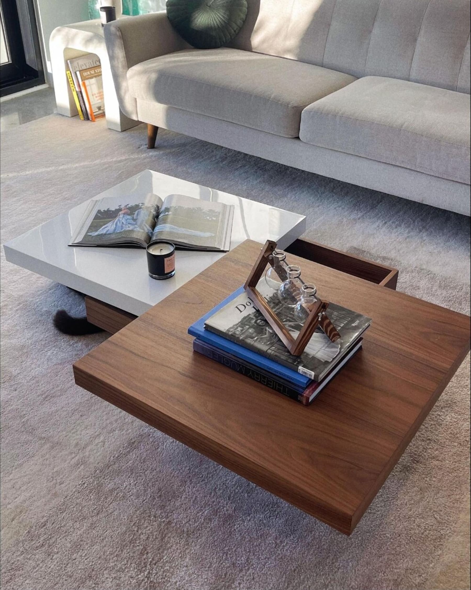 A rotatable coffee table with magazines, a candle, and a decorative piece.