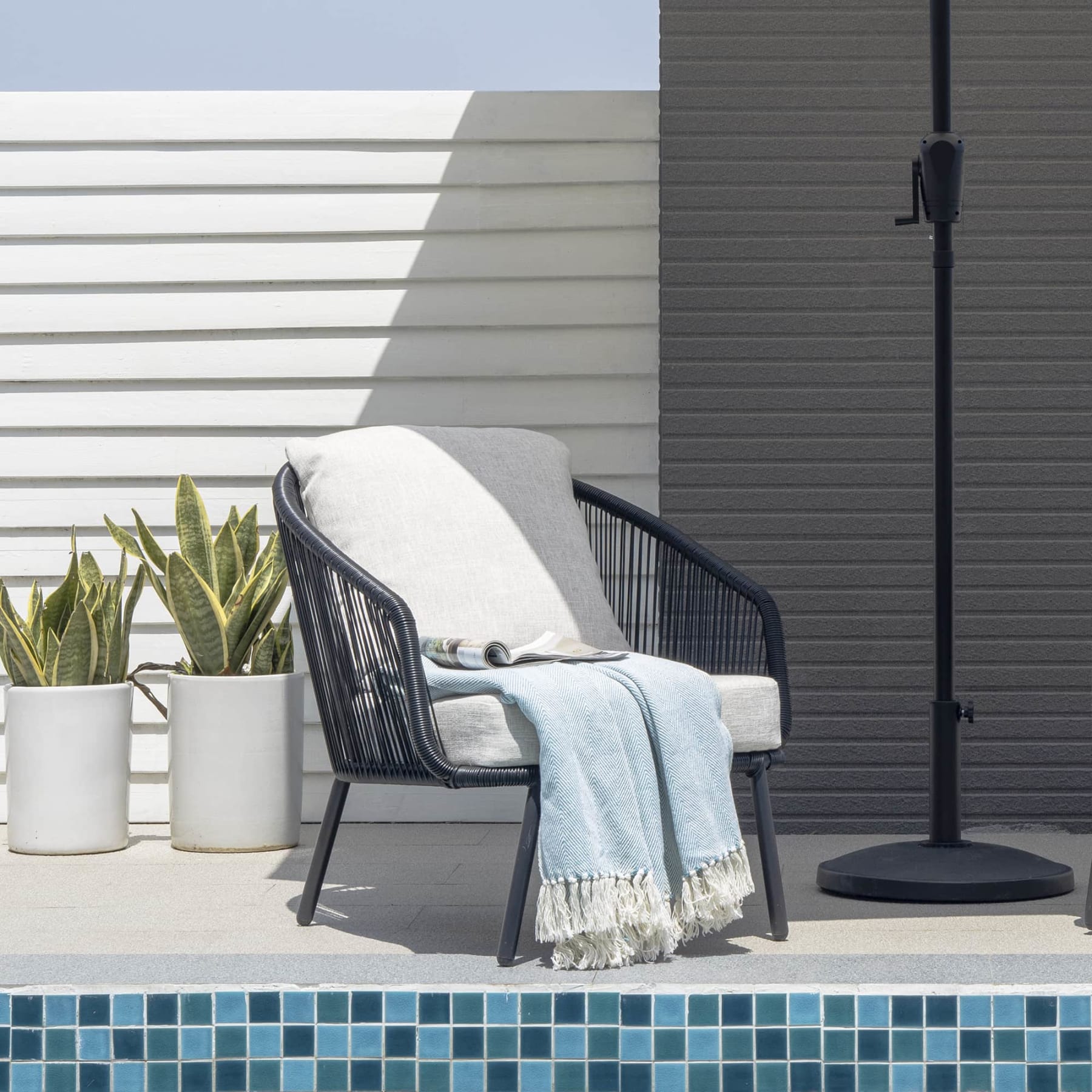 A weaved lounge chair with a towel draped on its seat.