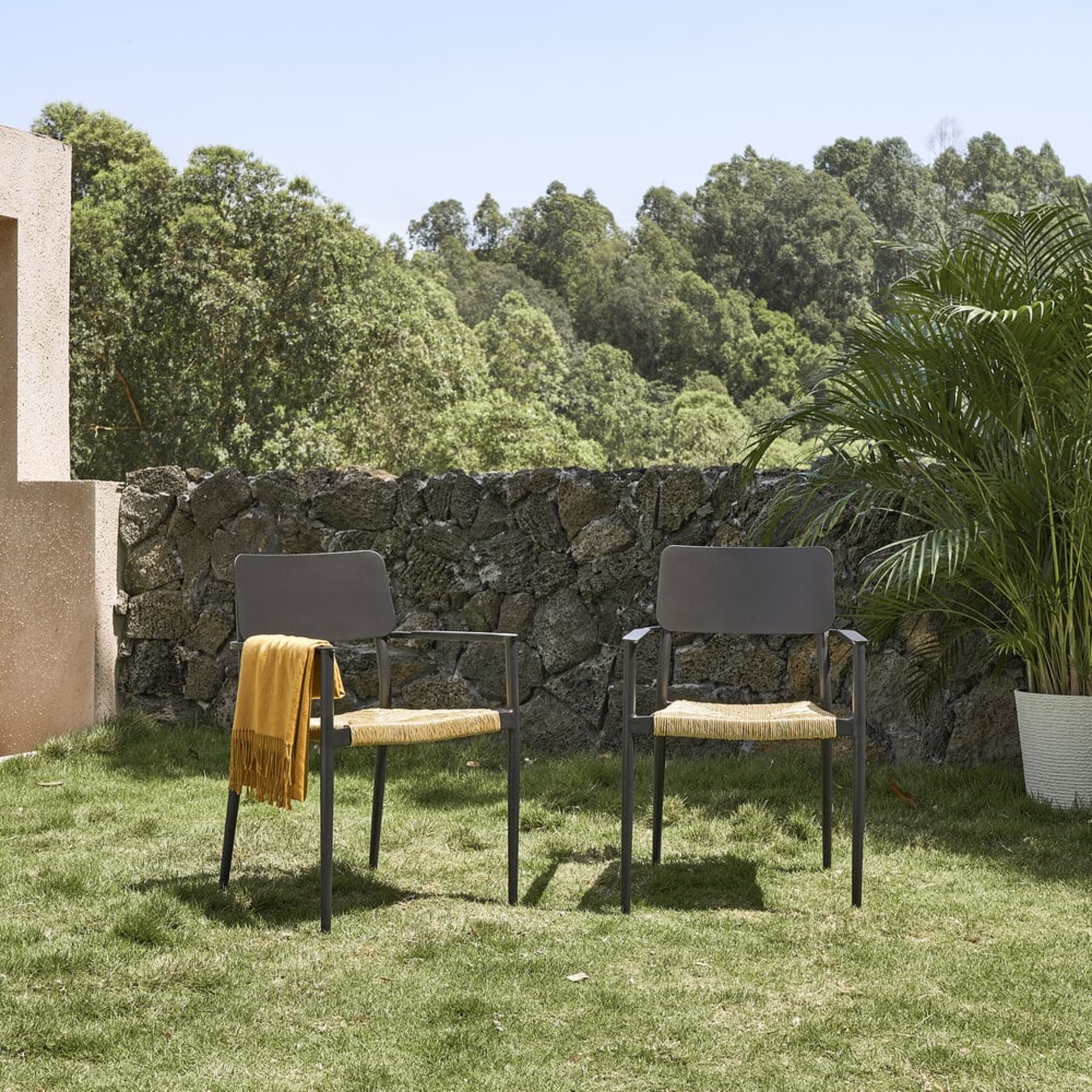 Two black outdoor dining chairs with woven wicker seats.