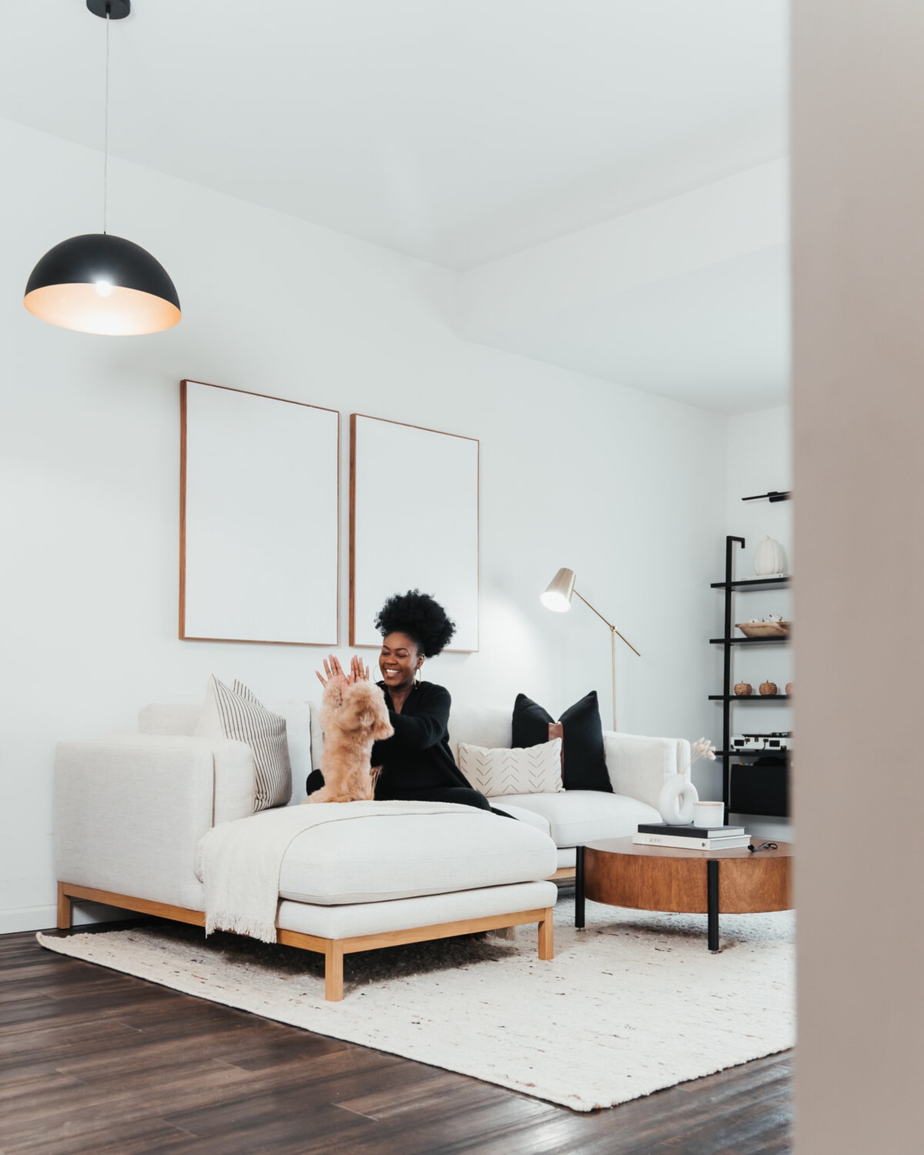 A person is placing accent pillows on a white fabric sofa.