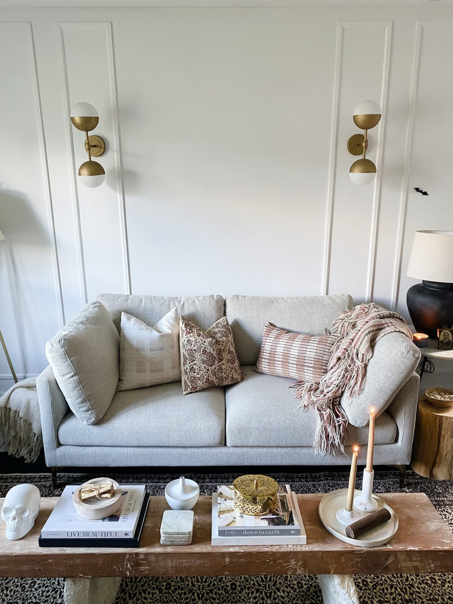 A gray loveseat with complementing cushions and a throw blanket.