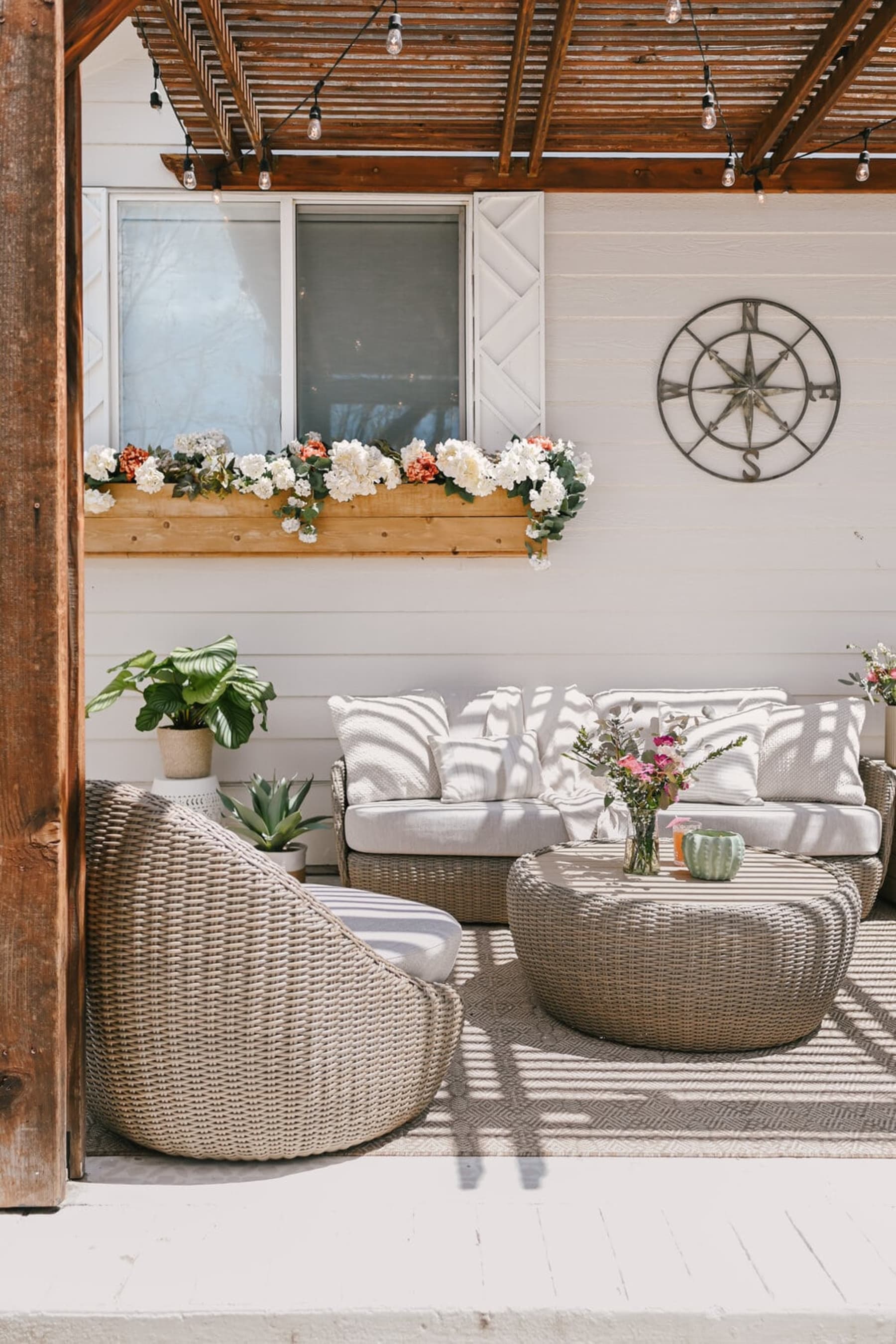 A wicker outdoor lounge set sits under a shade on a deck.