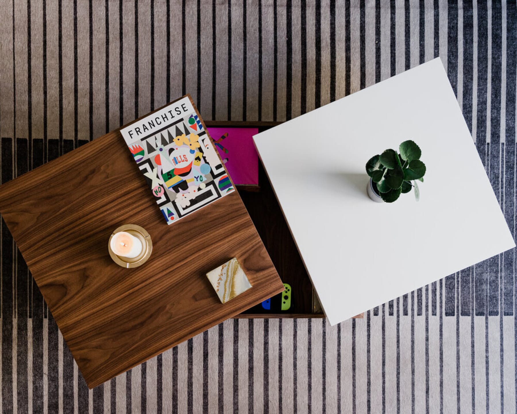 A wooden coffee table with drawers has decorative items on top.