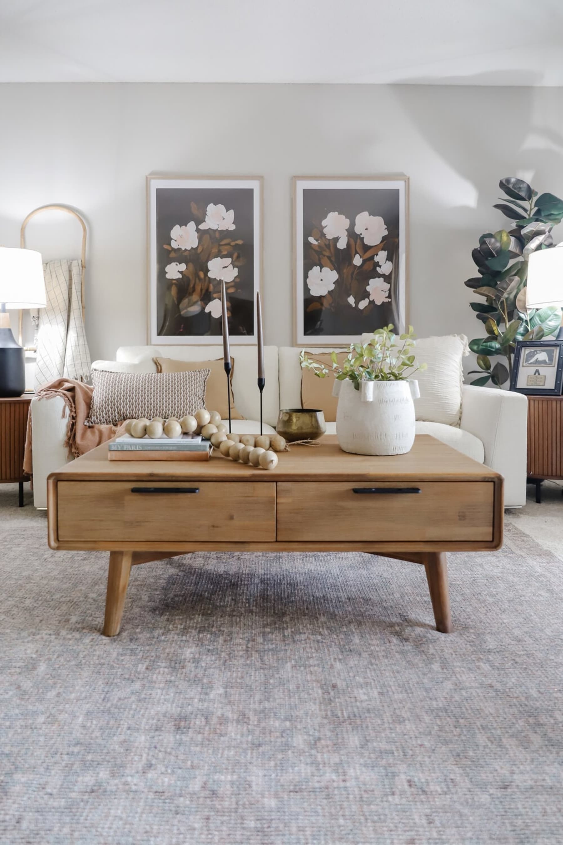 A wooden coffee table with drawers has decorative items on top.