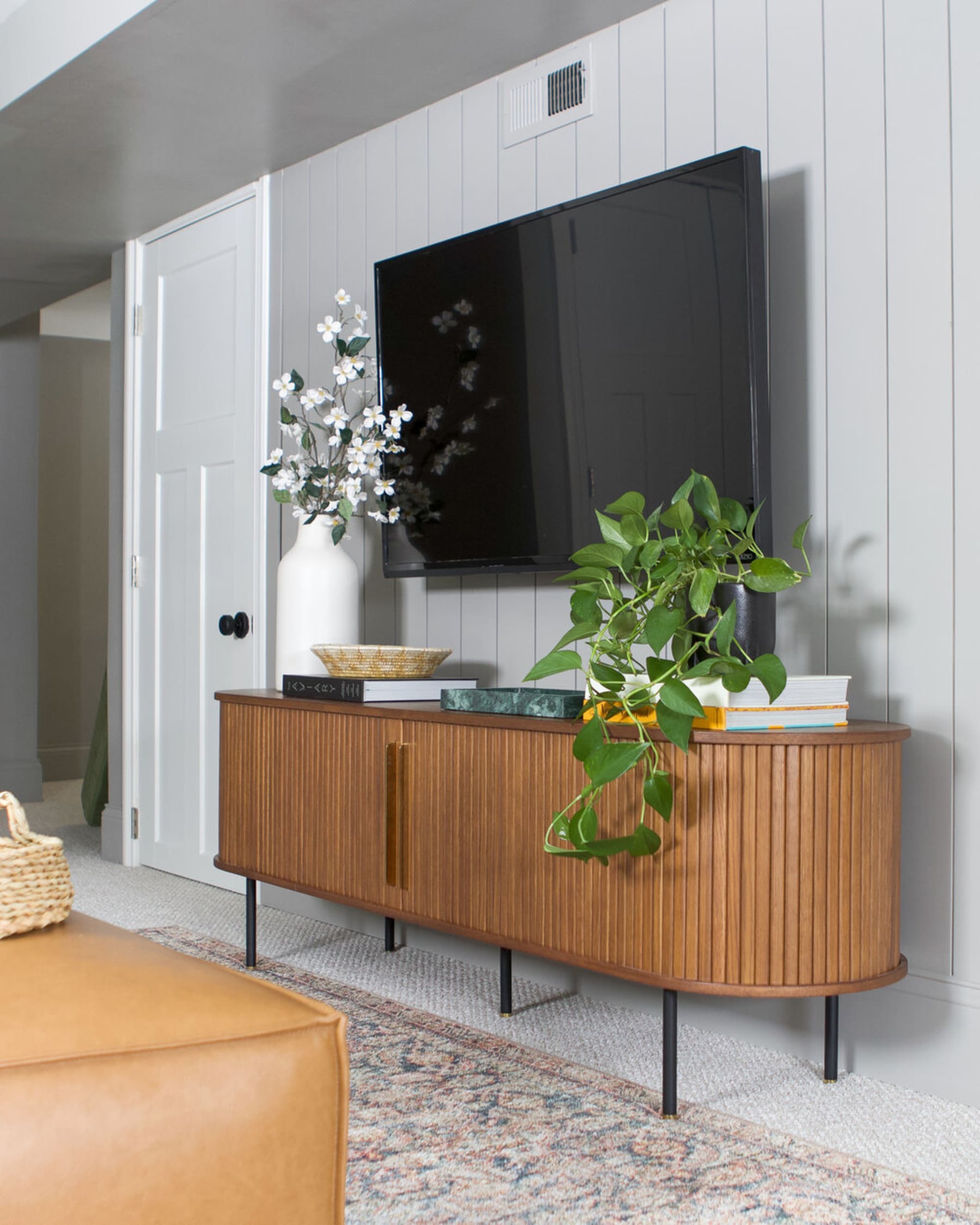 A TV stand with tambour doors with decorative pieces atop.