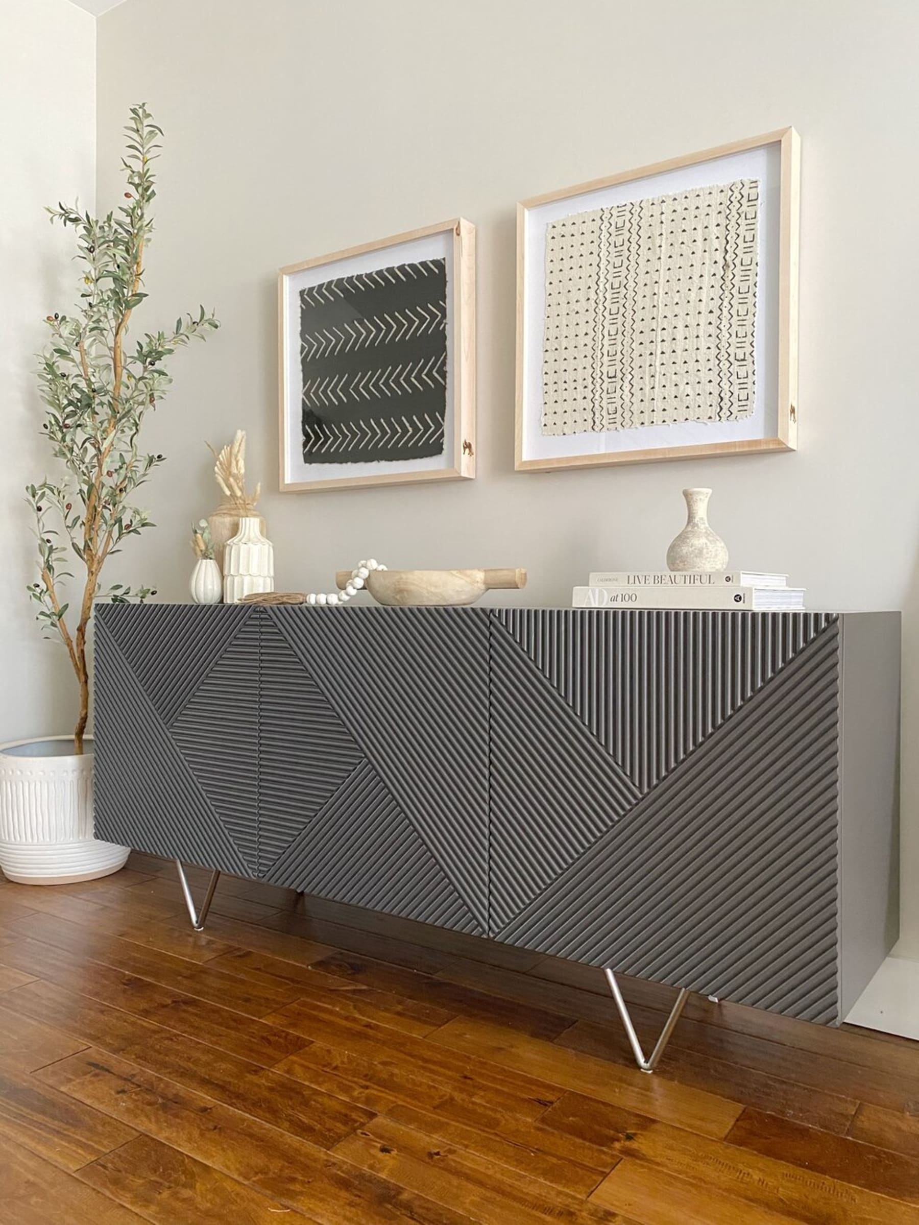 A black sideboard with stainless steel legs has decorative objects on top.