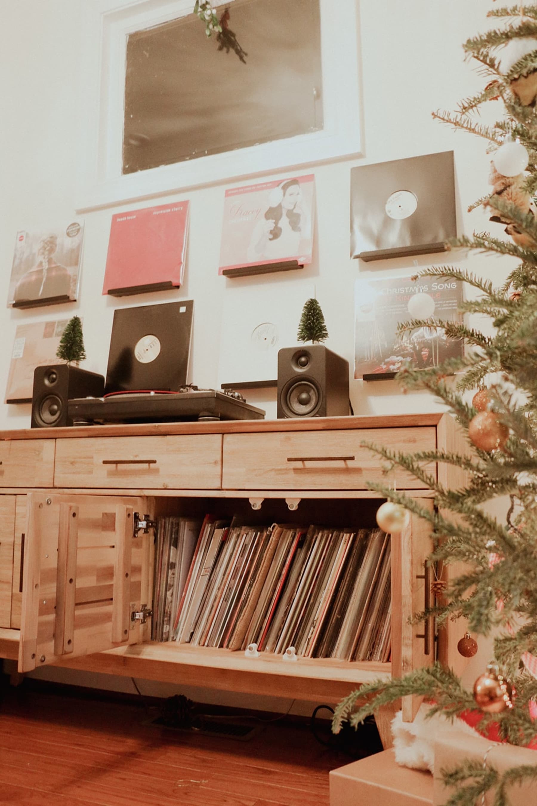 A wooden sideboard with its cabinets open shows several record players neatly organized.