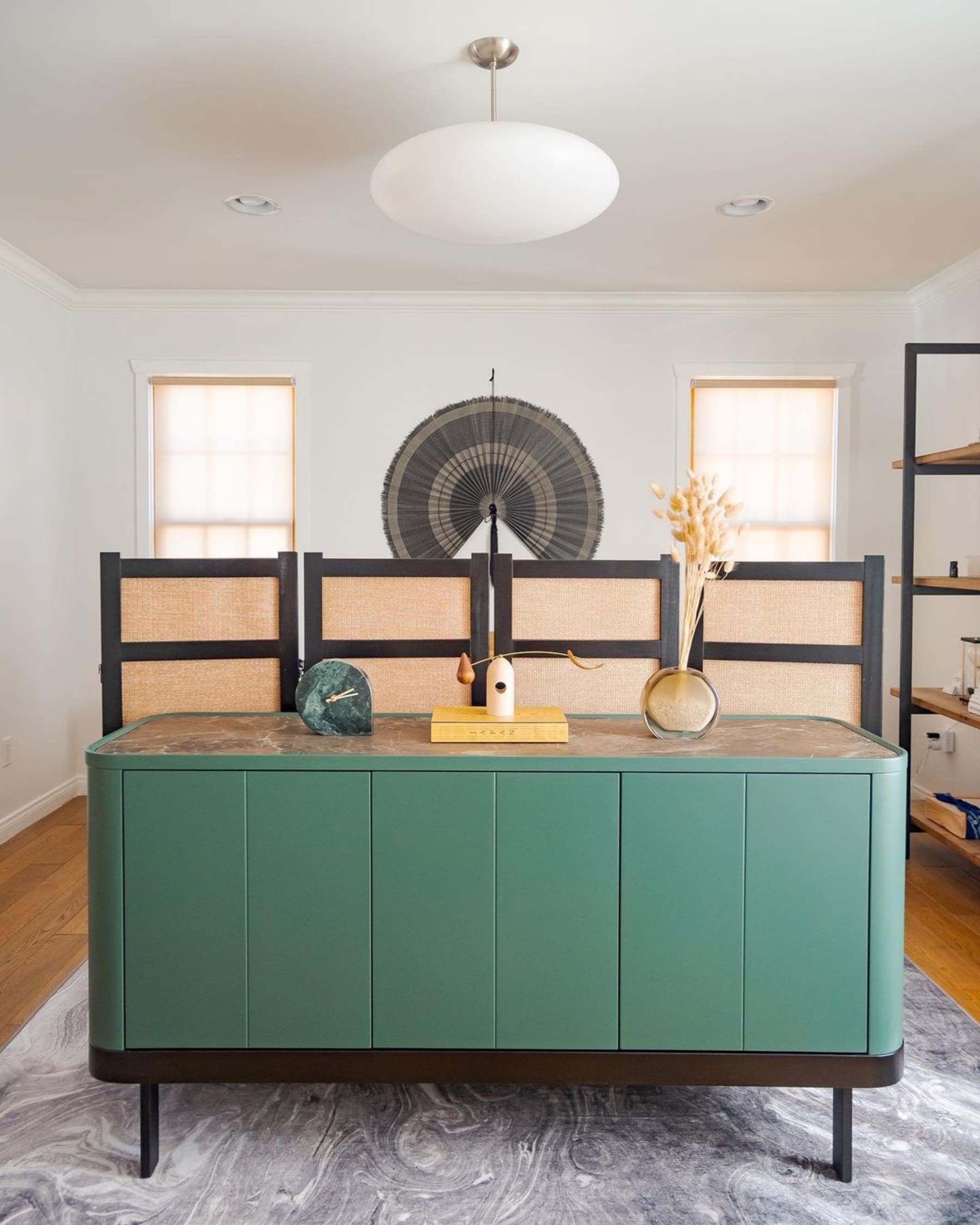 A green sideboard with a ceramic tabletop has decorative ornaments atop.