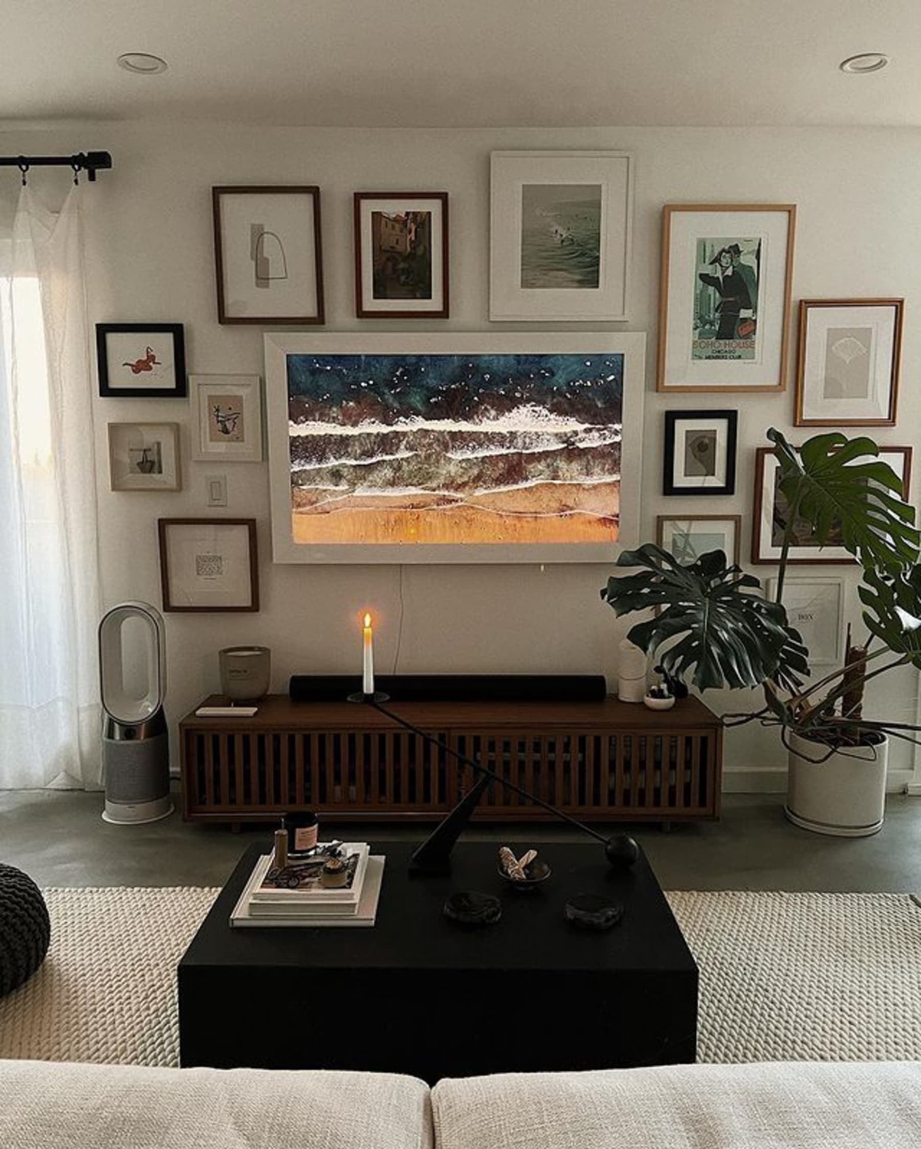 Wooden TV unit with slatted doors surrounded by wall art