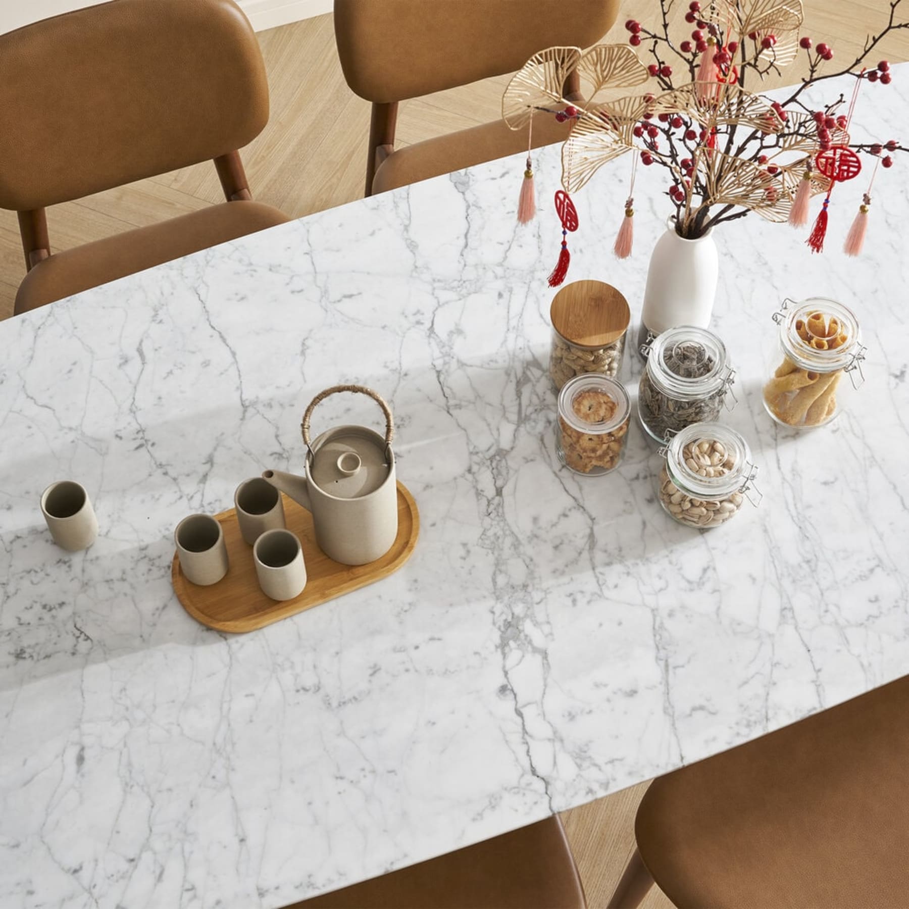 A marble dining table with jars of snacks and a teapot with matching cups.