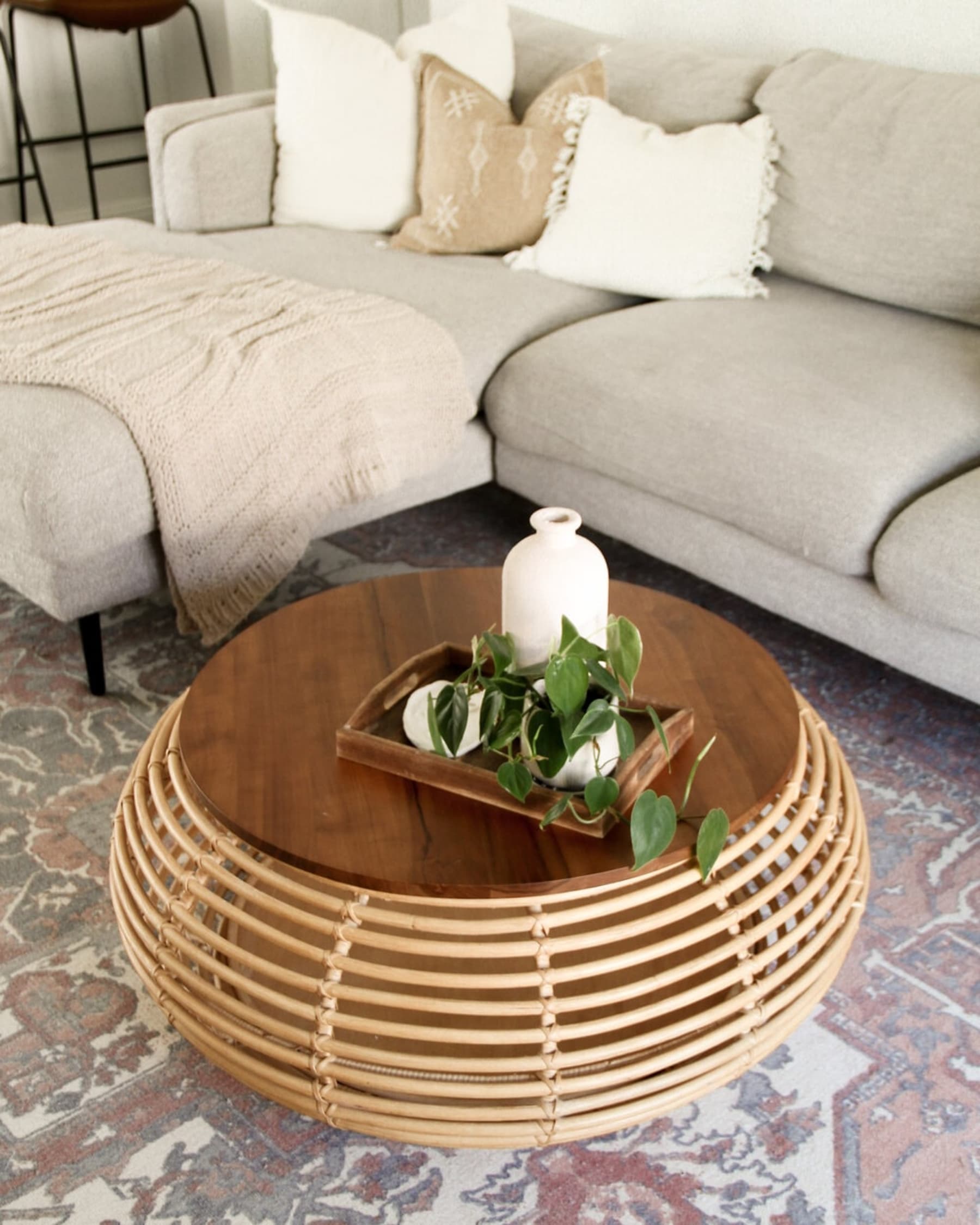 A wooden tray with a potted plant and decorative objects on a rattan coffee table.