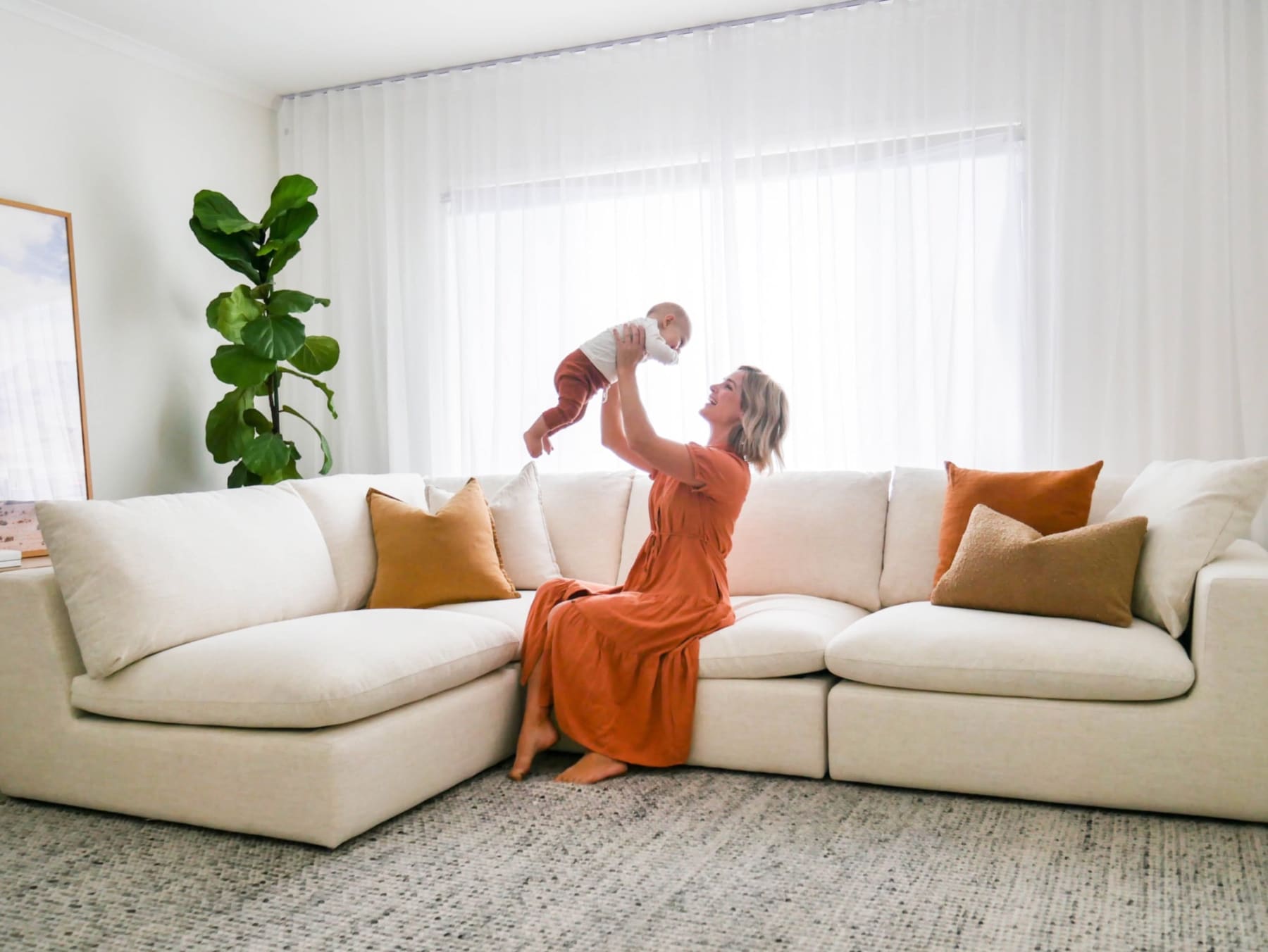 A person is playing with a baby on a white fabric sectional sofa.