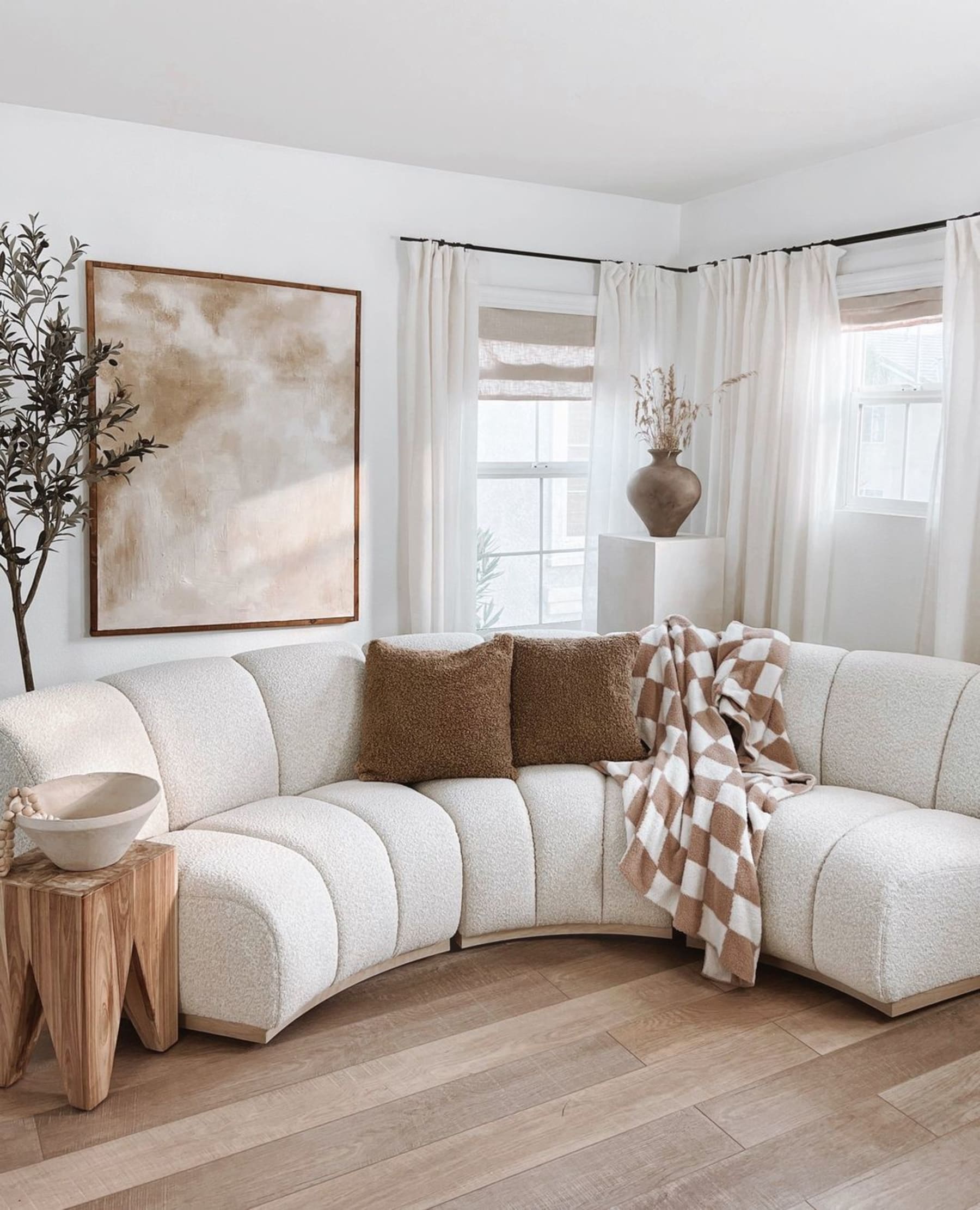 A bouclé sofa with brown cushions and a throw.