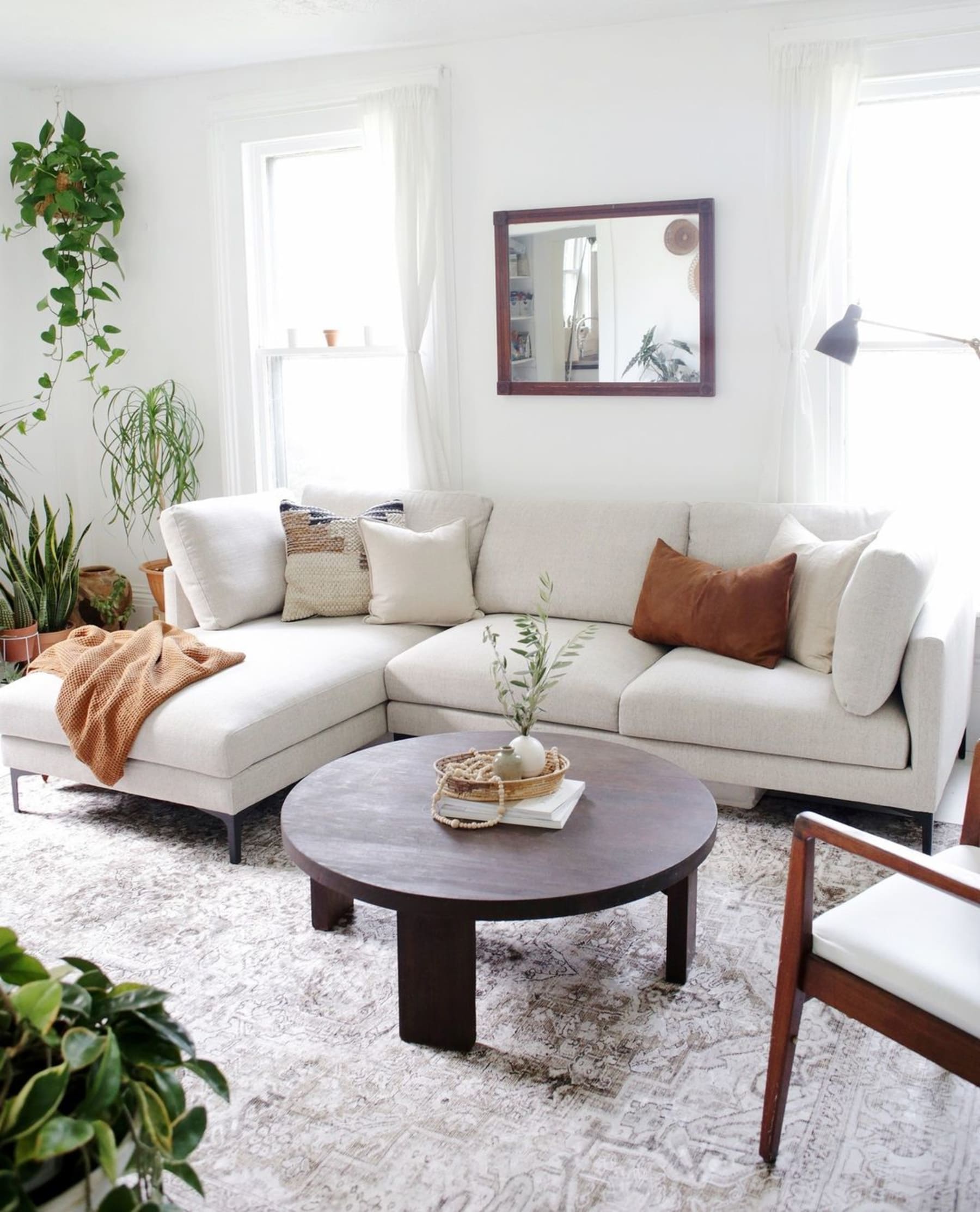 A white fabric sectional sofa with a brown throw and matching brown cushion.