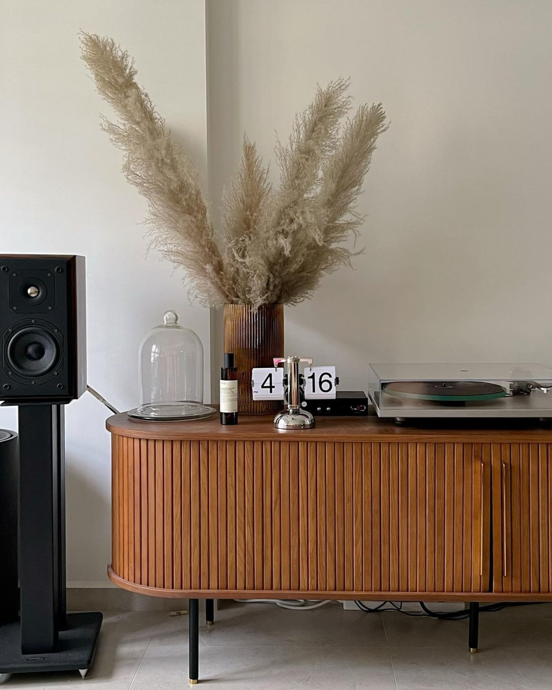 A TV stand with a record player, a vase, and other decor on top.