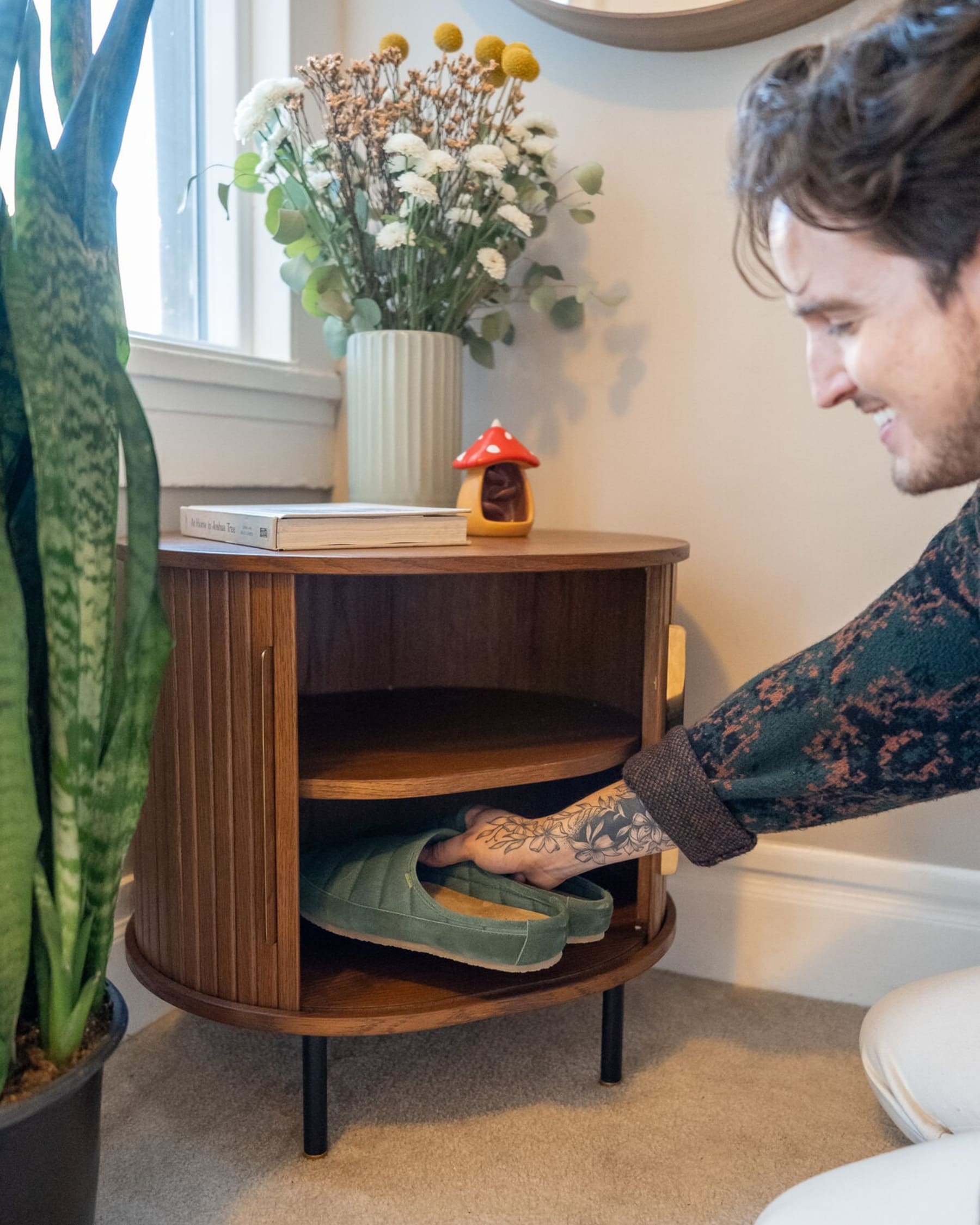 A person is keeping bedroom slippers in the side table storage.