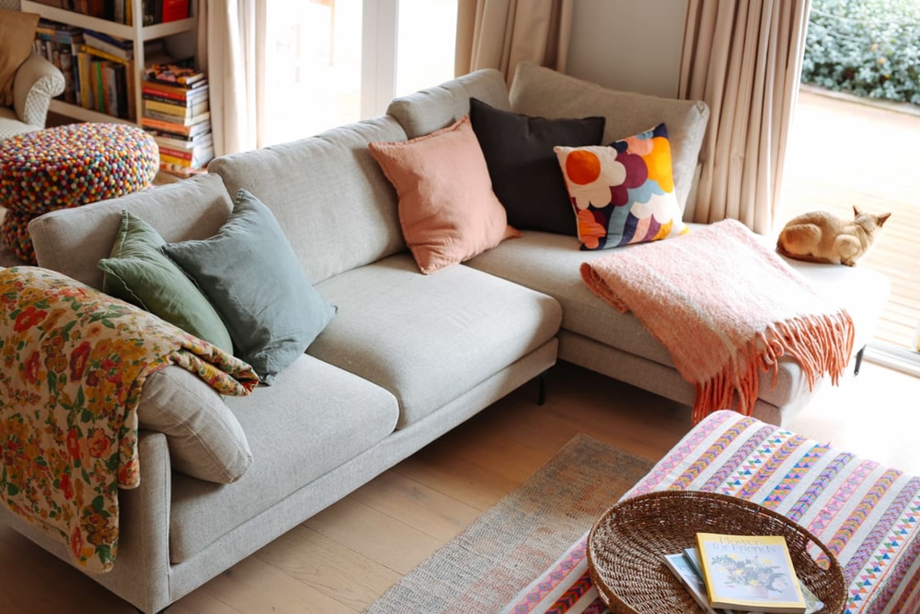 A sectional sofa with different colored and patterned cushions and throws.