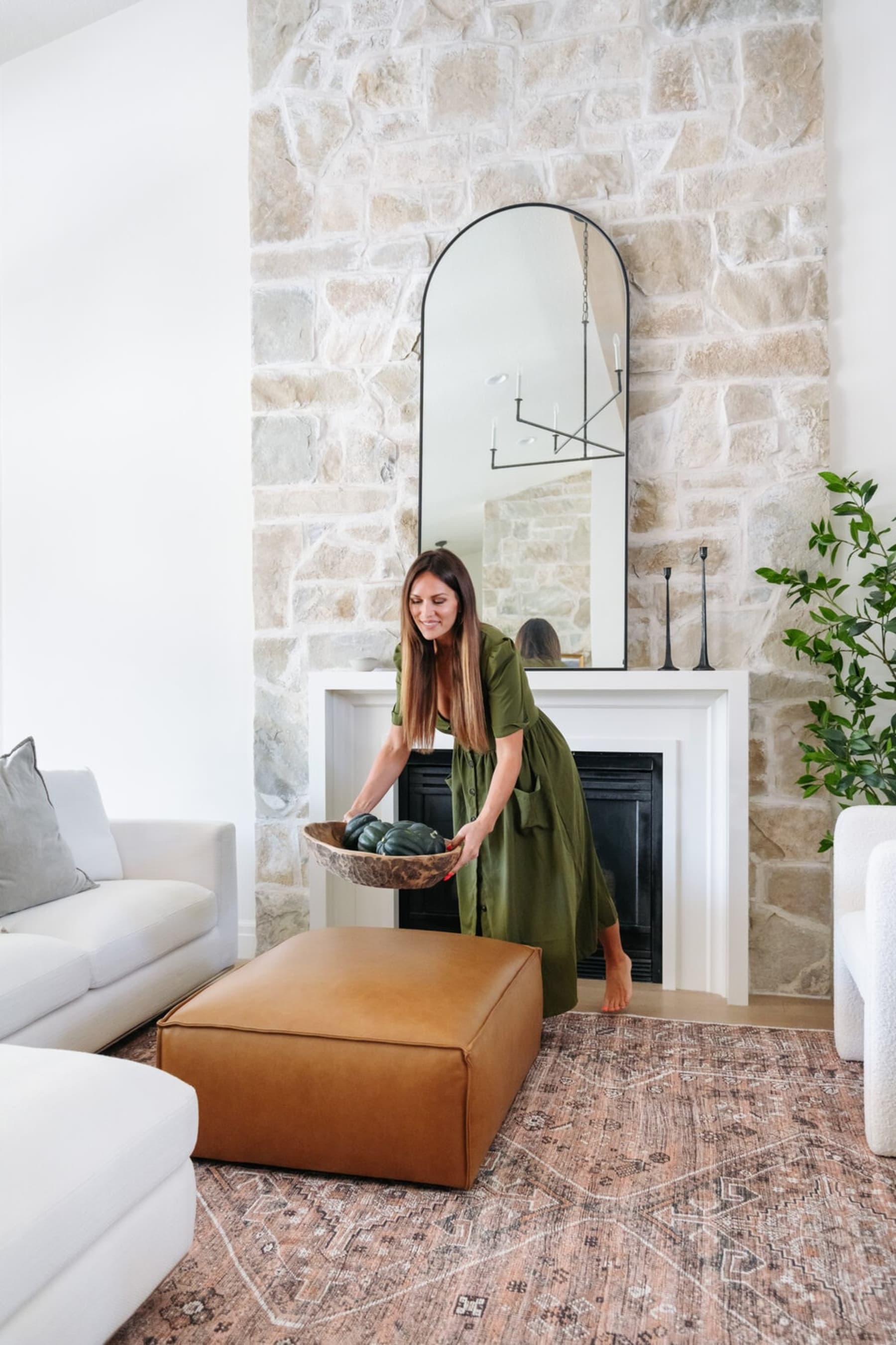 A person is placing a decorative bowl on a leather ottoman.