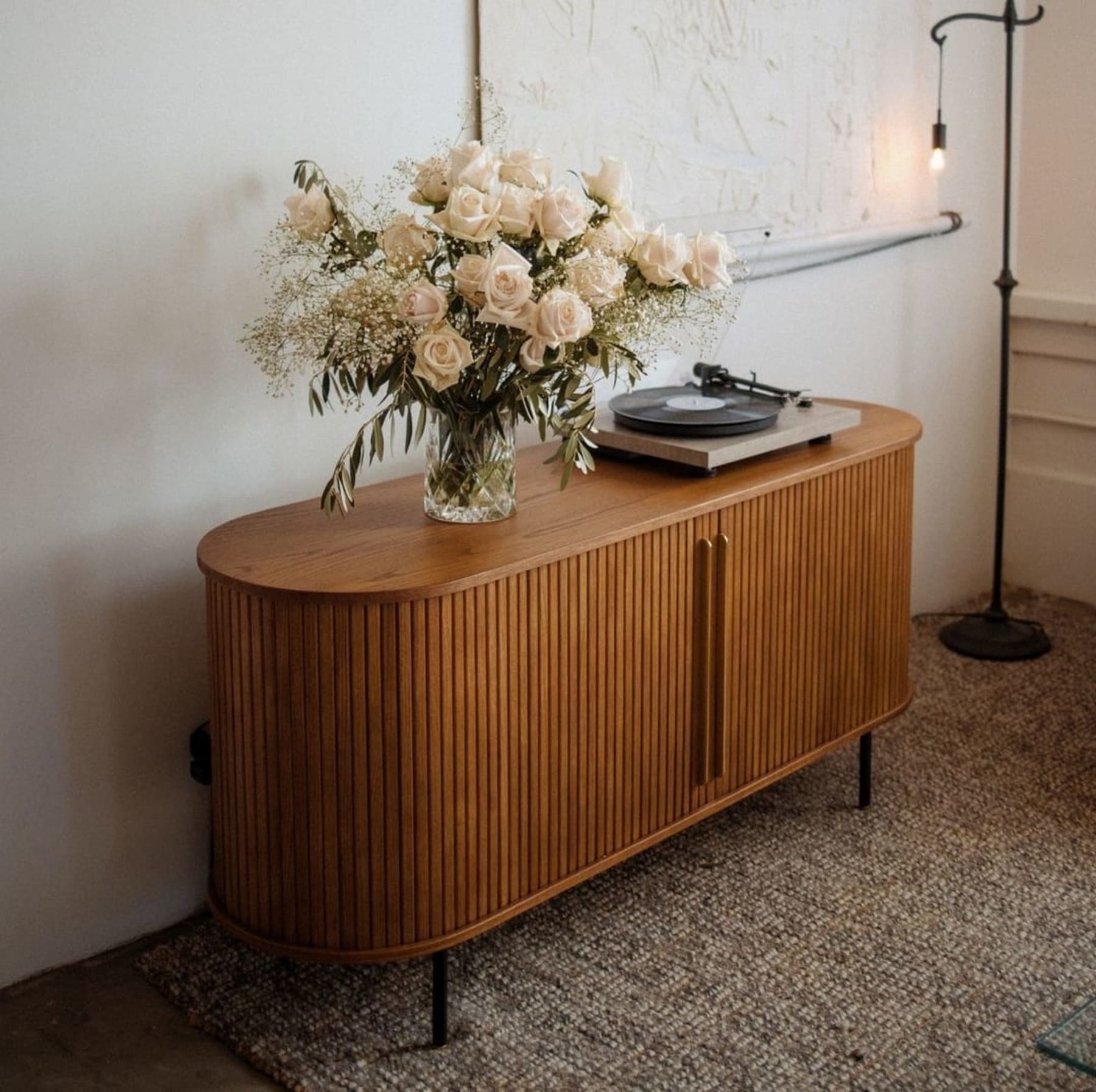 A wooden sideboard with a vase and a record player on top