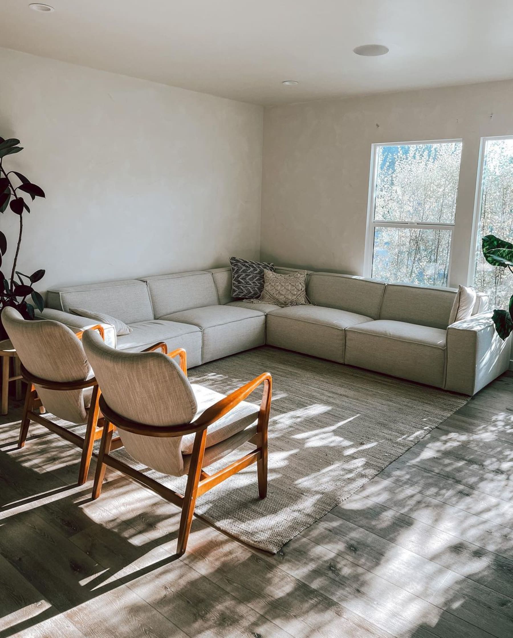 An L-shaped white sectional sofa and 2 armchairs.