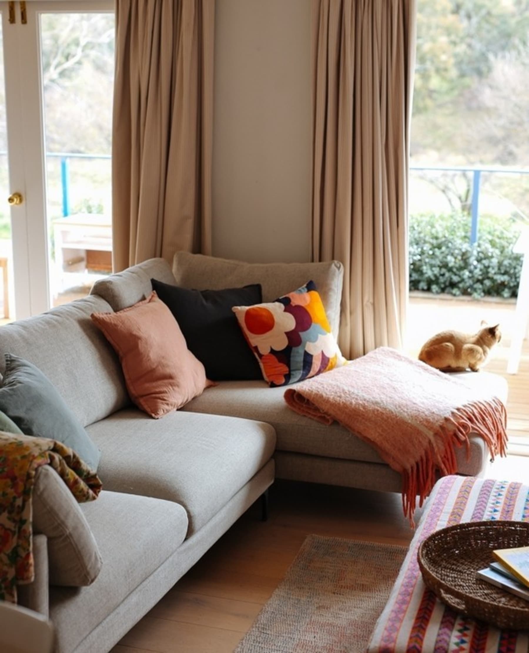 A sectional sofa with a vibrant floral pillow, accompanied by other complementing cushions and a throw.