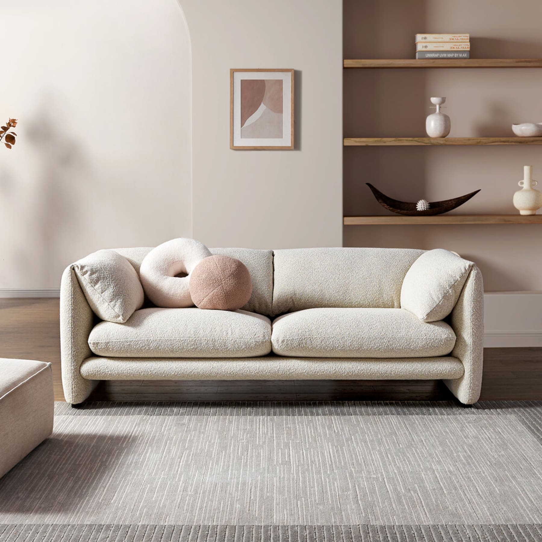 A performance bouclé sofa with 2 square cushions, a round cushion, and one that resembles a donut.