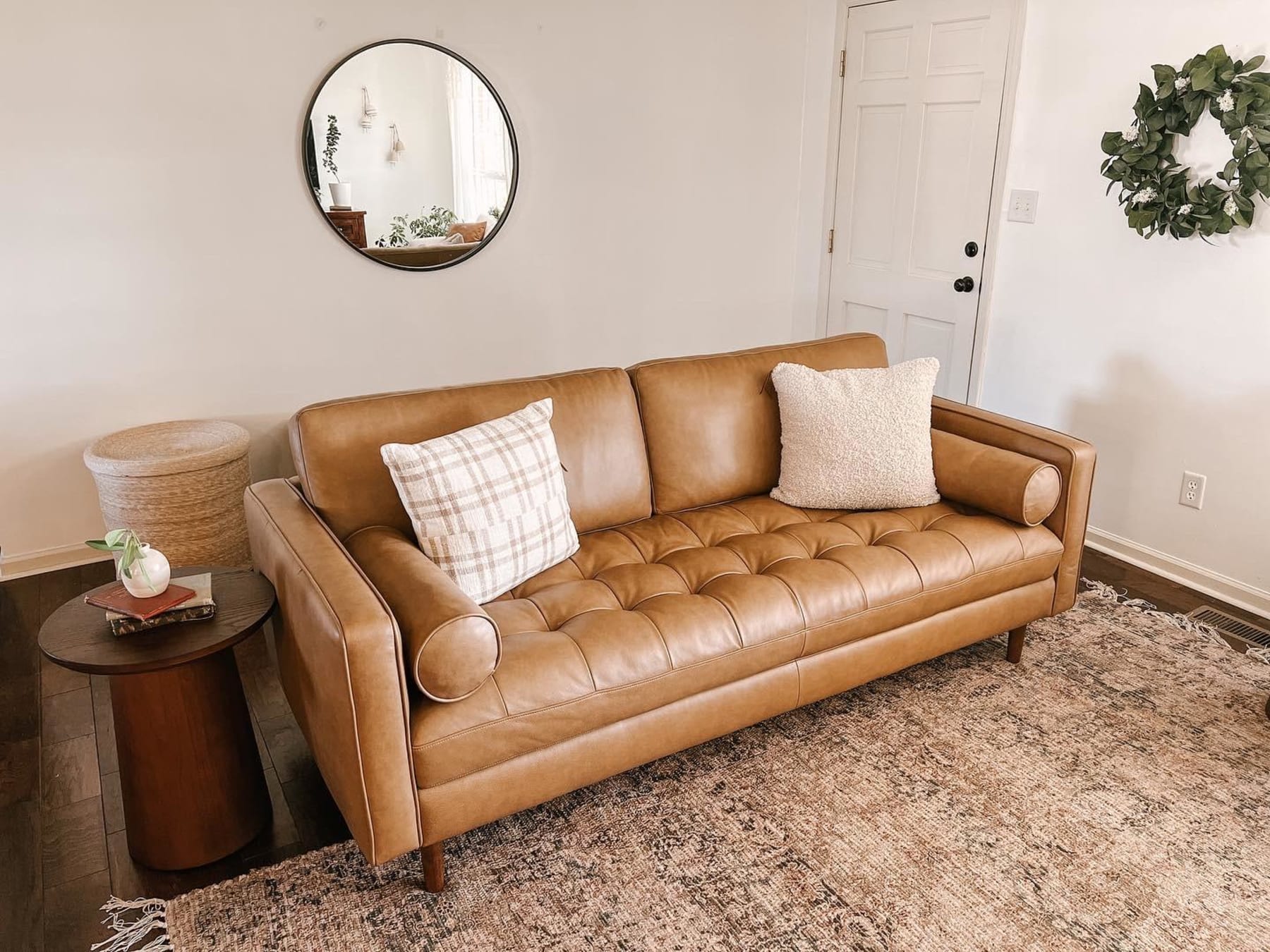 A leather 3-seater sofa with 2 cushions and a wooden side table.