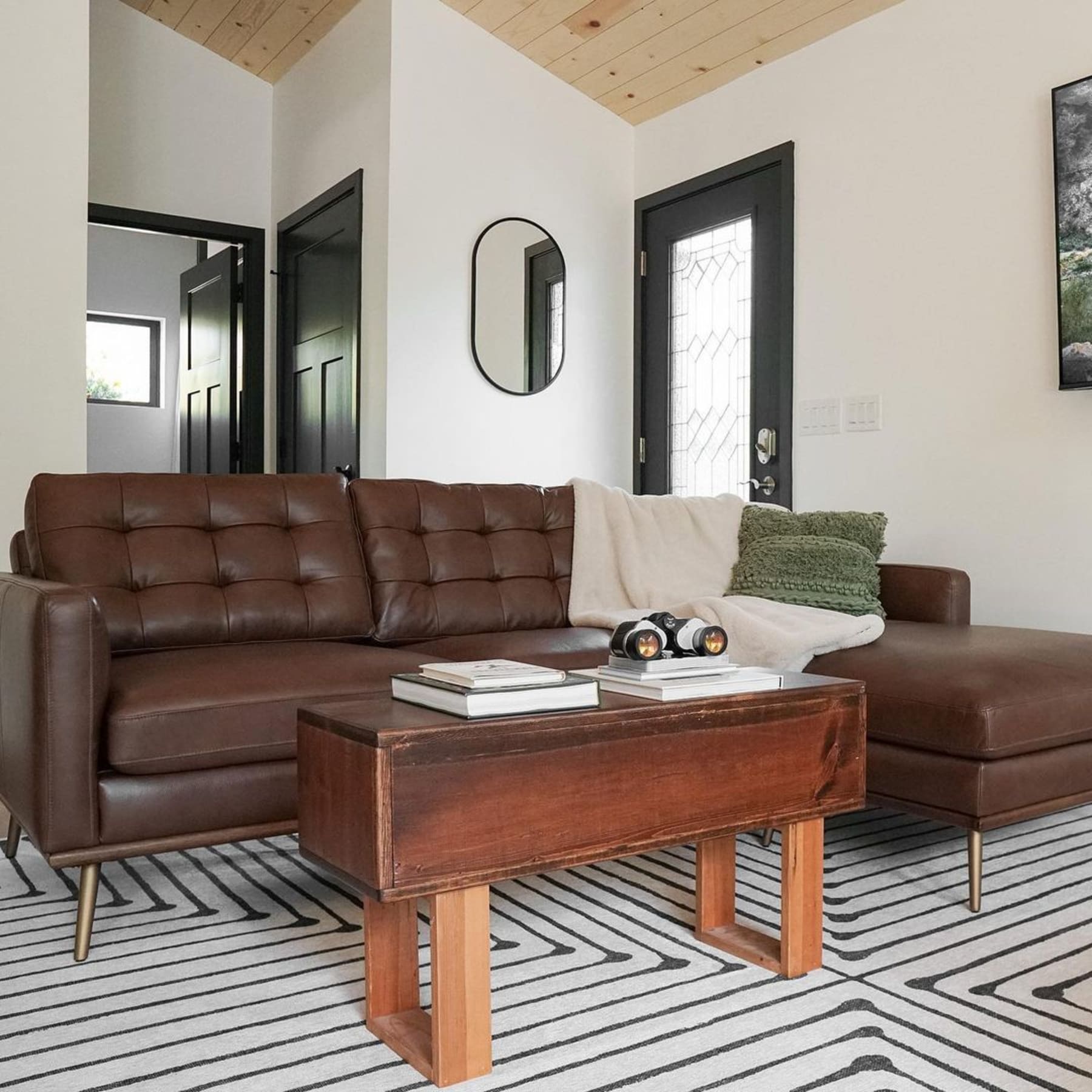 A tufted leather sofa with a throw and green cushion.