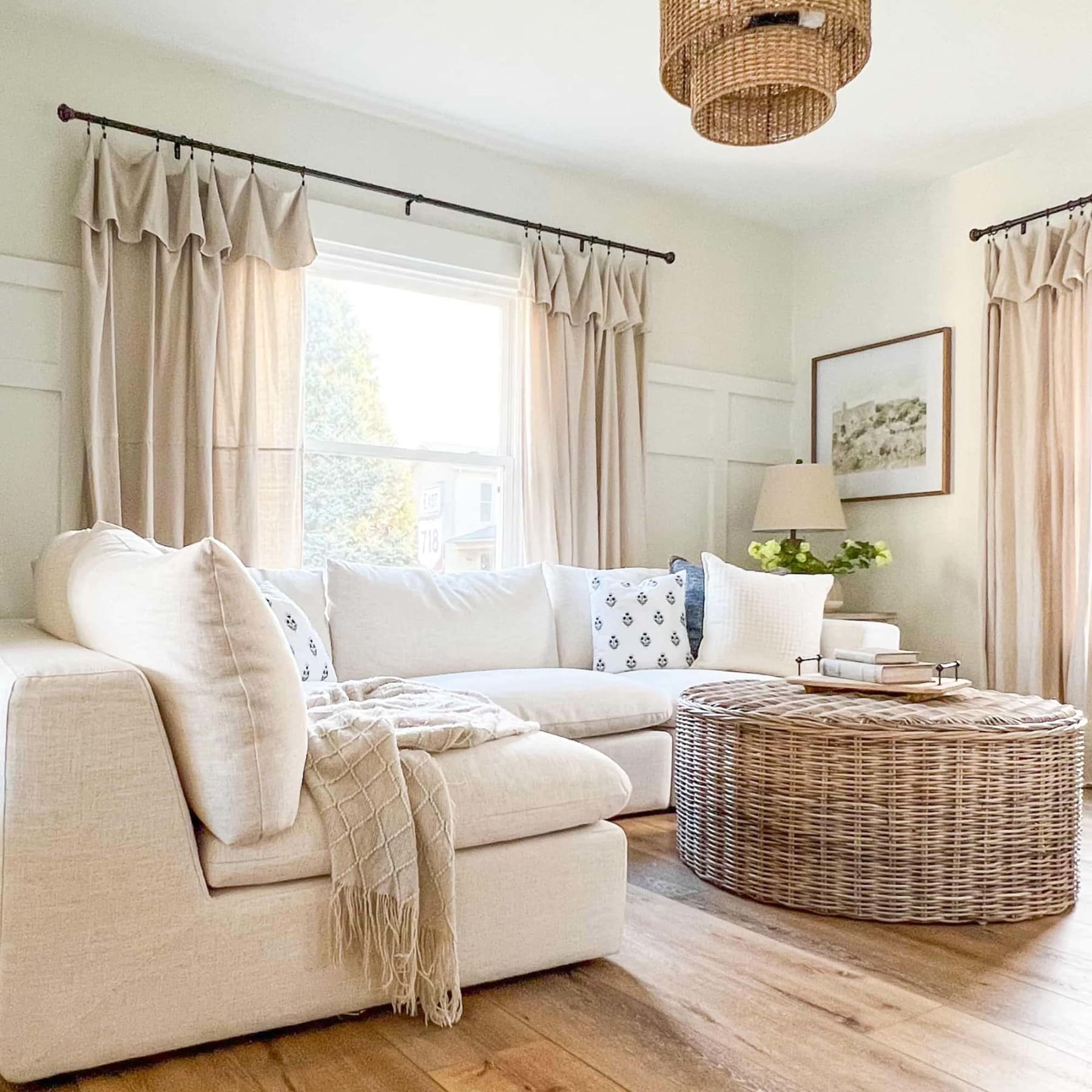 A white sectional sofa and a woven coffee table sit in a living room.