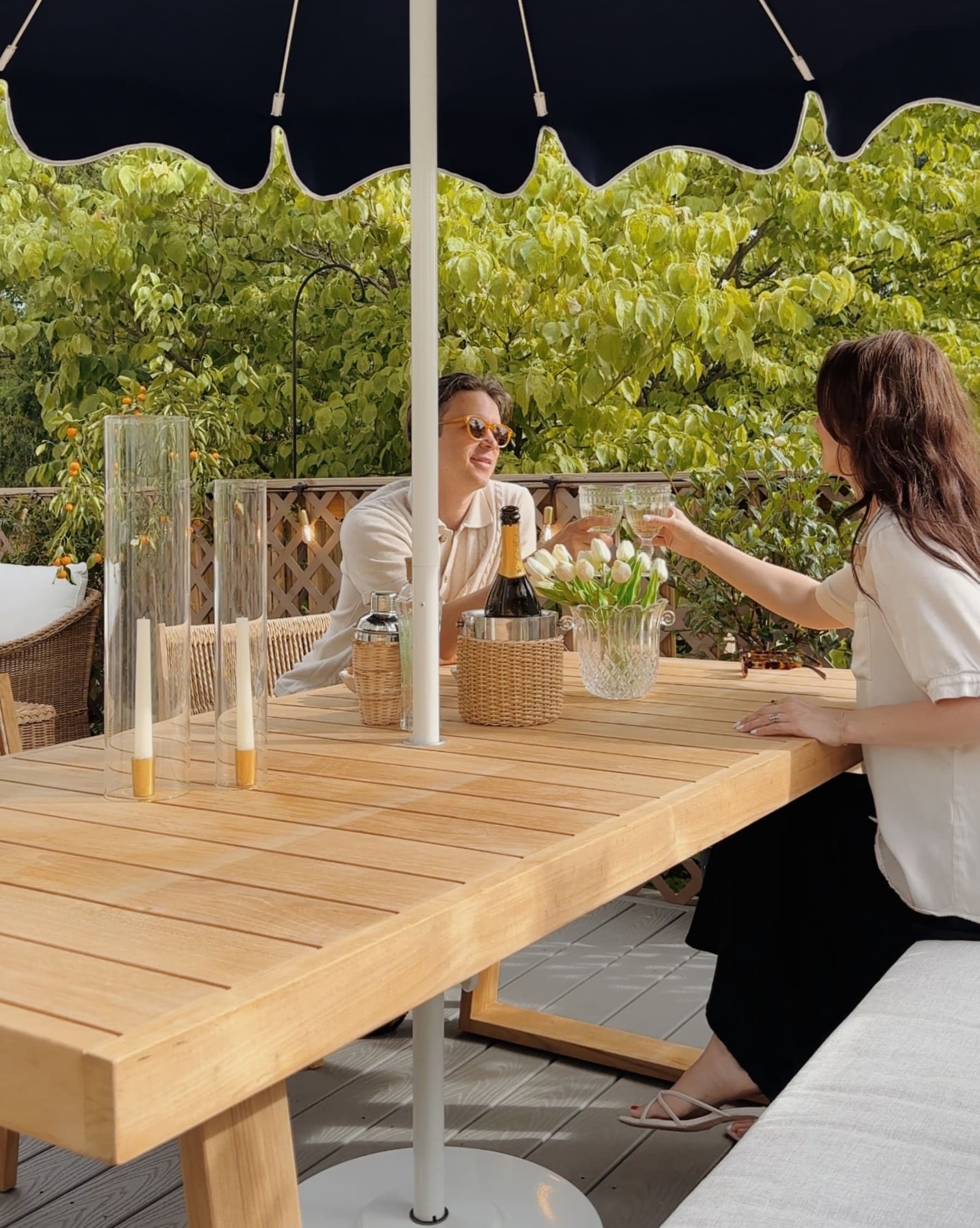 Two people sit on a teak dining table and bench.