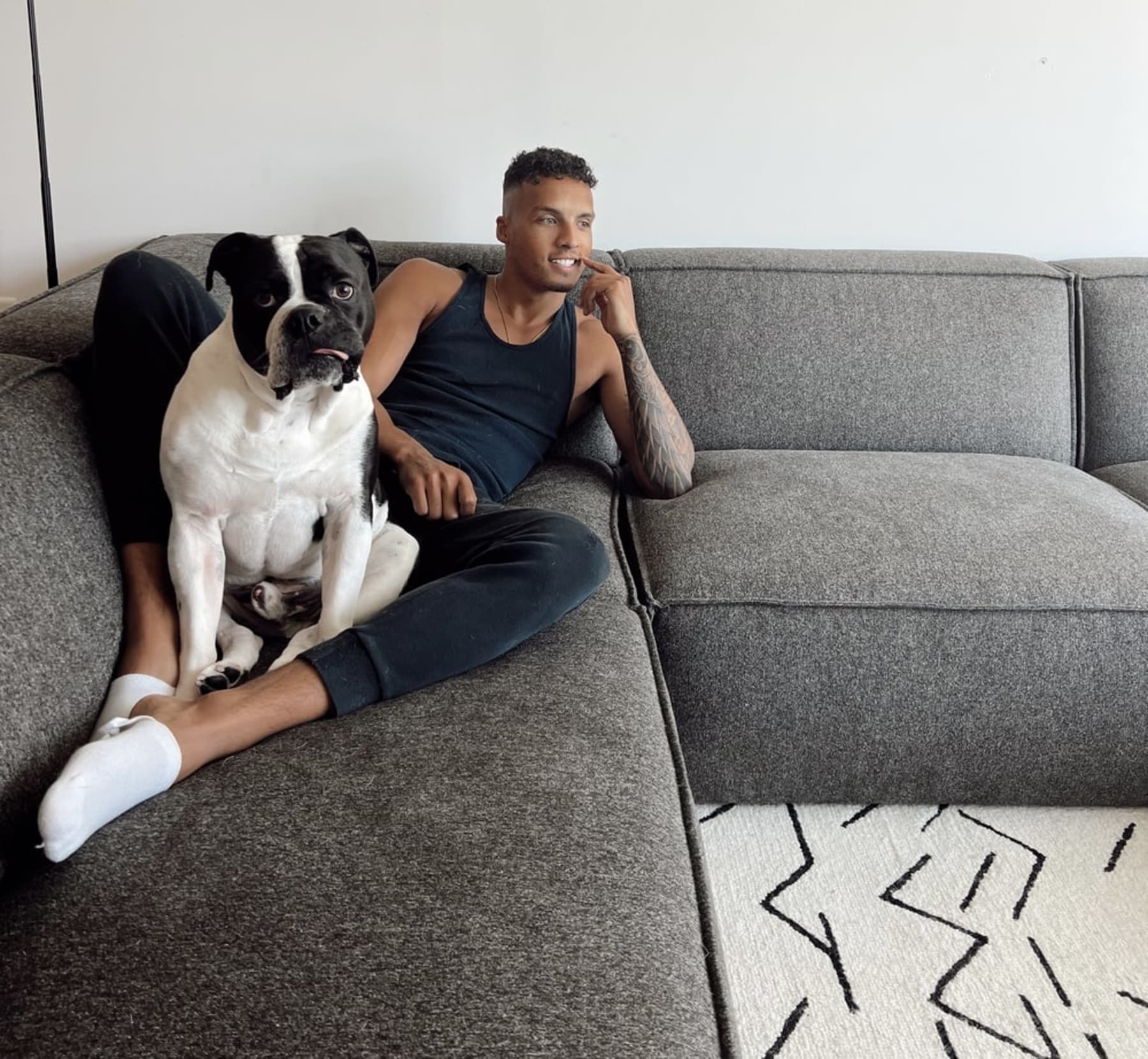 A person lounging with their dog on a gray sectional sofa.